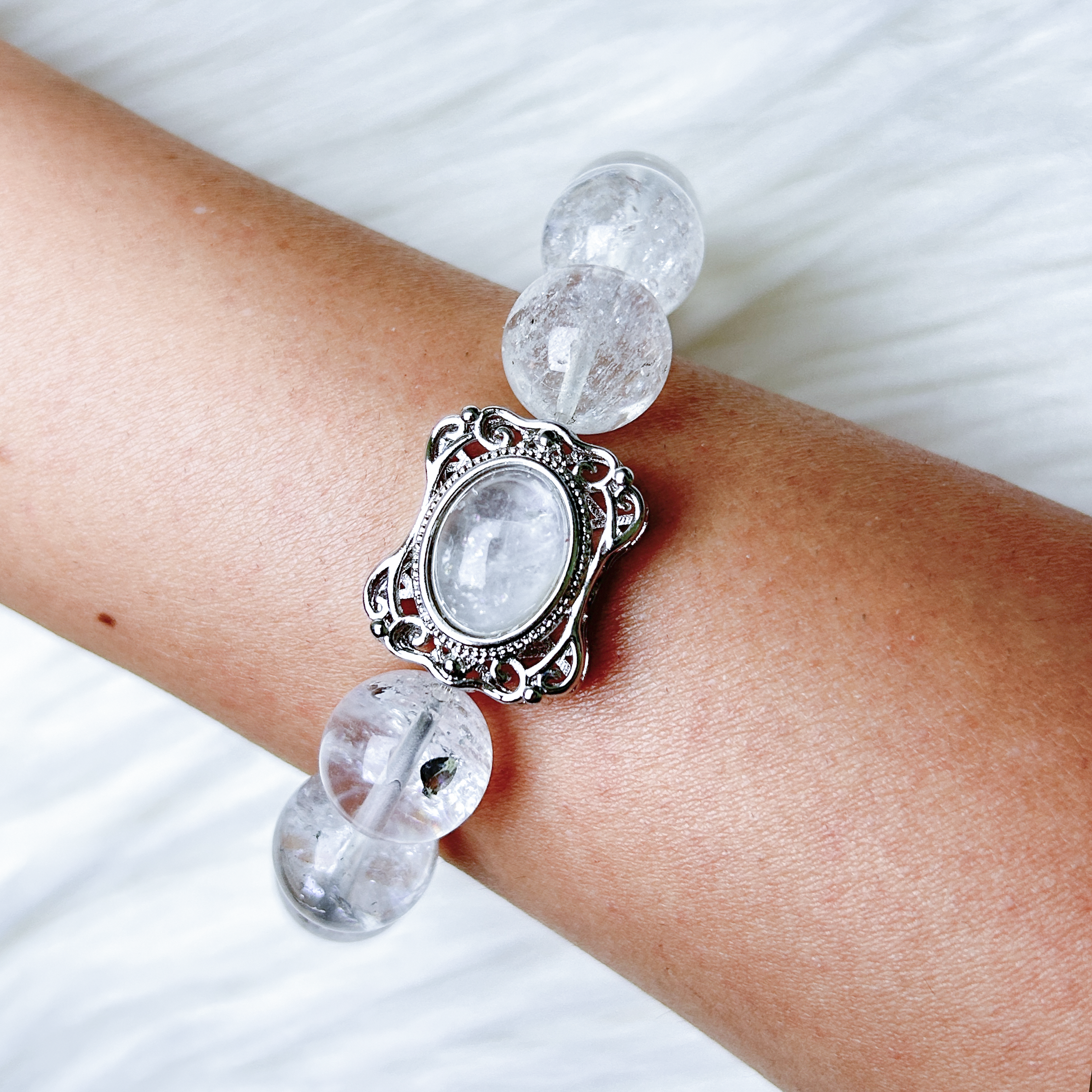 Close-up of rutilated quartz centerpiece framed in silver on the Blossom Valley bracelet worn on wrist