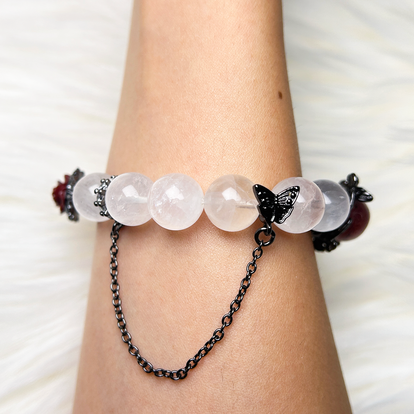 Blushing Elegance bracelet worn on wrist showing butterfly chain accent and round quartz beads.