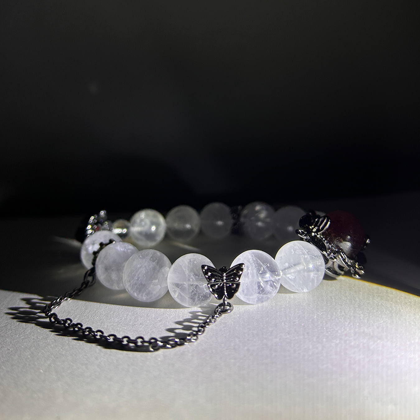 Blushing Elegance bracelet with white rutilated quartz and butterfly charm under soft light.