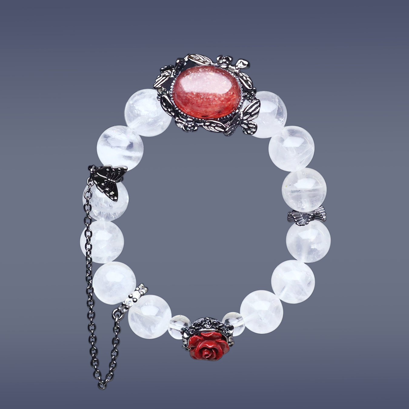 Full view of a handcrafted bracelet featuring white phantom quartz beads, a sunstone centerpiece in a black floral frame, red rose charm, butterfly chain, and delicate silver accents on a gradient background.
