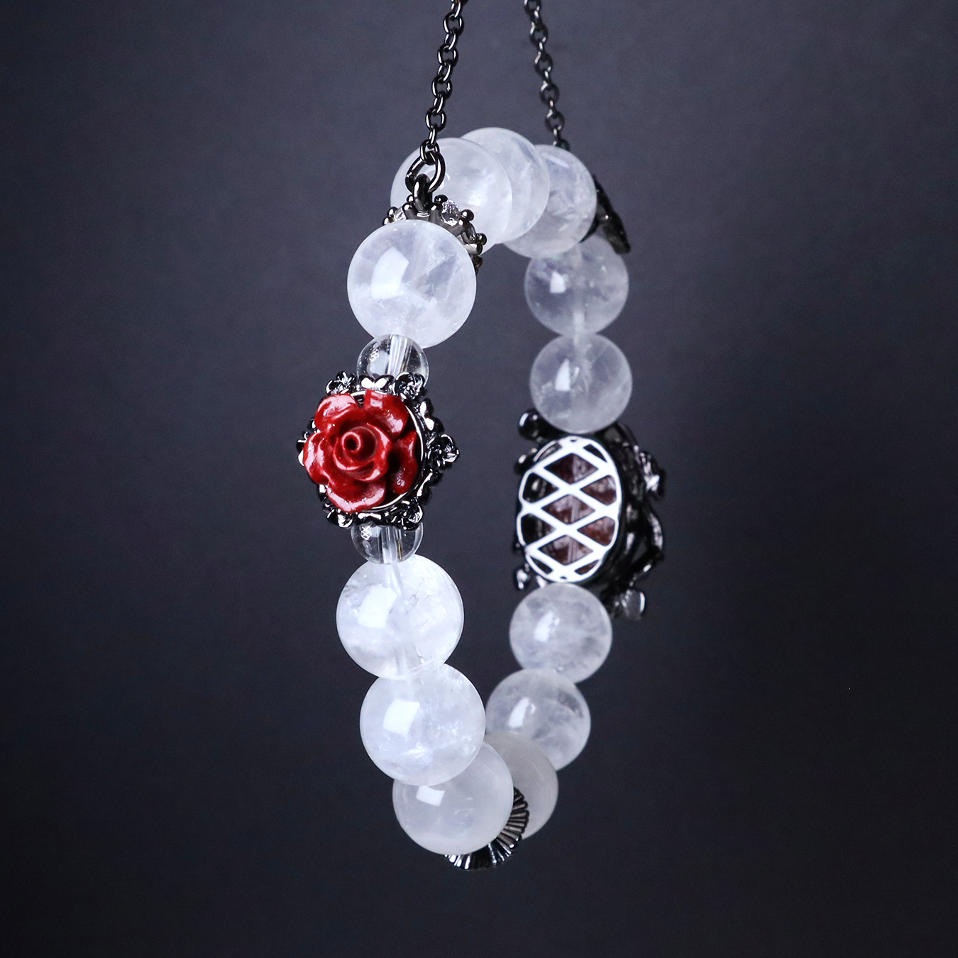 Angled view of the bracelet highlighting the red rose charm, black butterfly chain, and intricate back setting of the sunstone centerpiece against a dark backdrop.