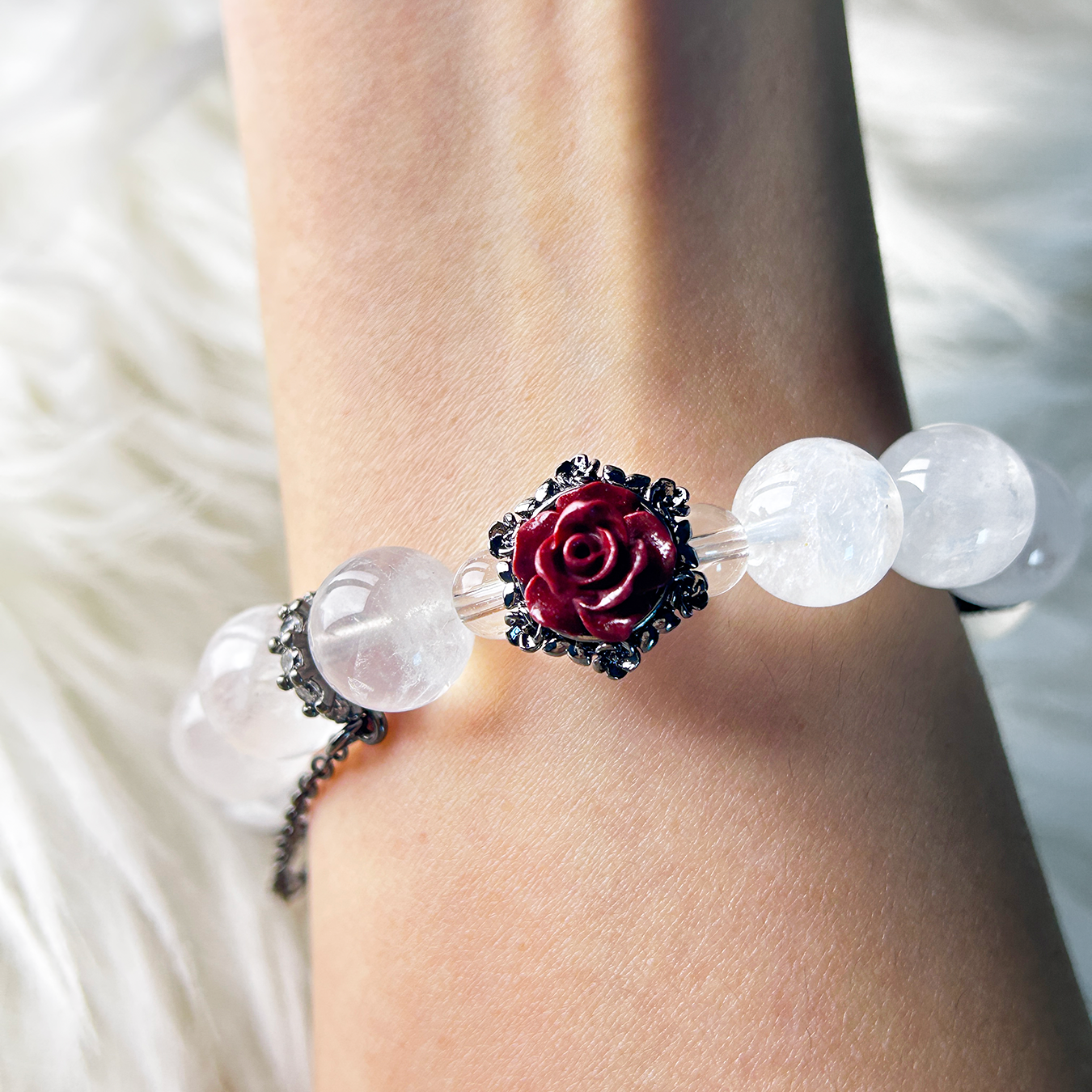 Wrist shot showing the red rose charm and surrounding white phantom quartz beads, emphasizing the romantic and vintage-inspired design.