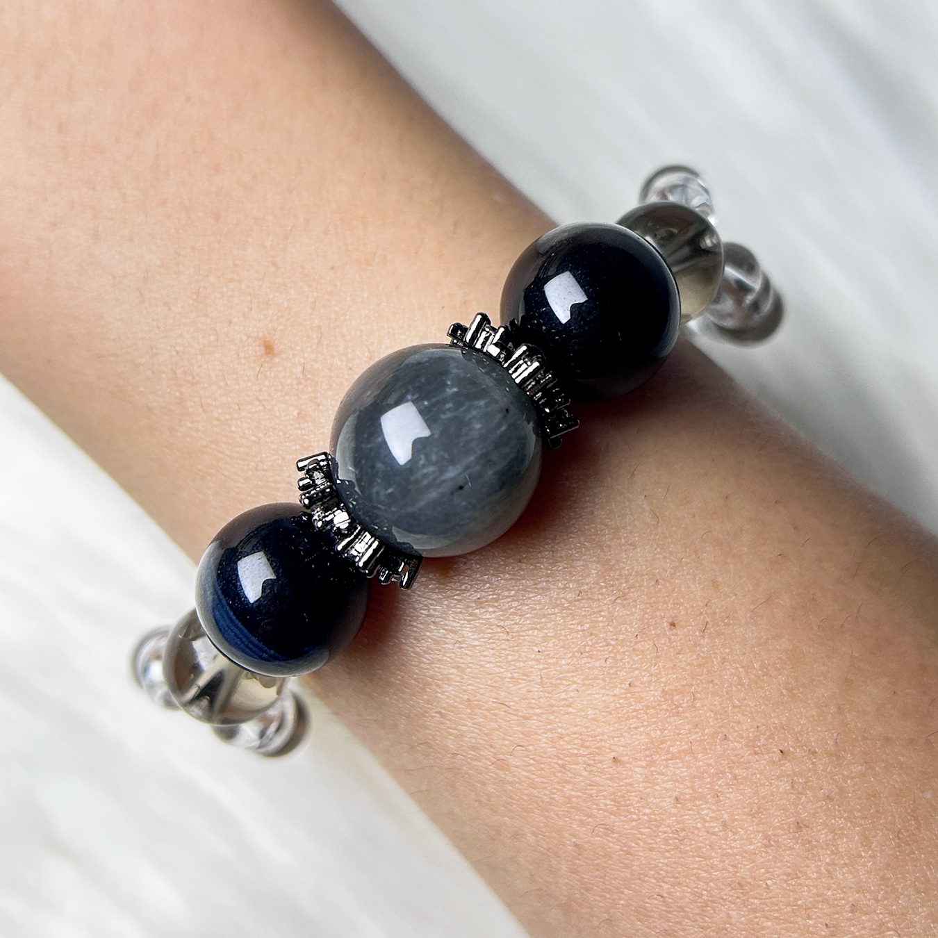 Handmade crystal bracelet featuring gray rabbit hair rutilated quartz centerpiece with blue tiger’s eye beads, elegant healing stone jewelry for protection and balance.