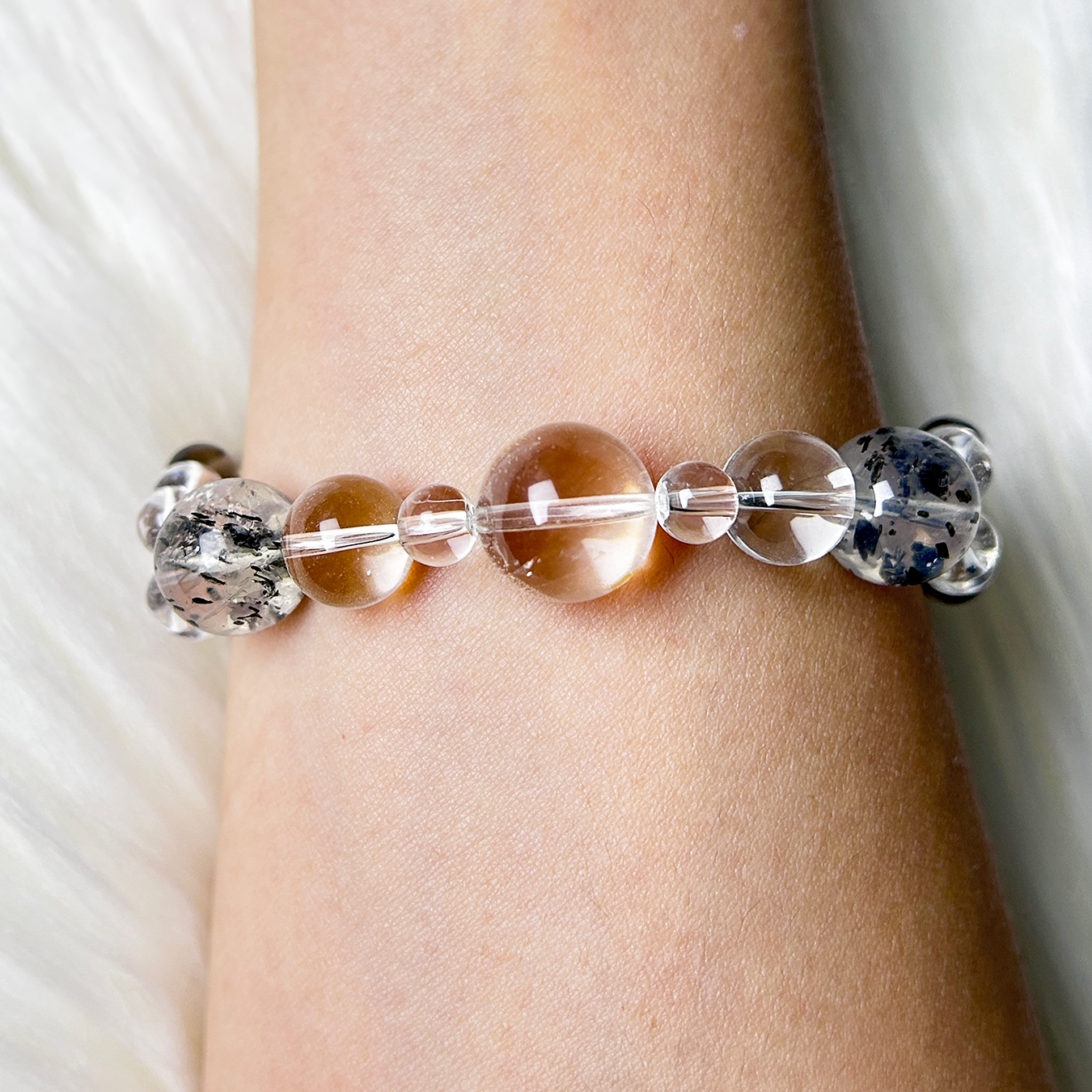 Crystal bracelet featuring different sizes of clear quartz and biotite mica quartz on wrist.