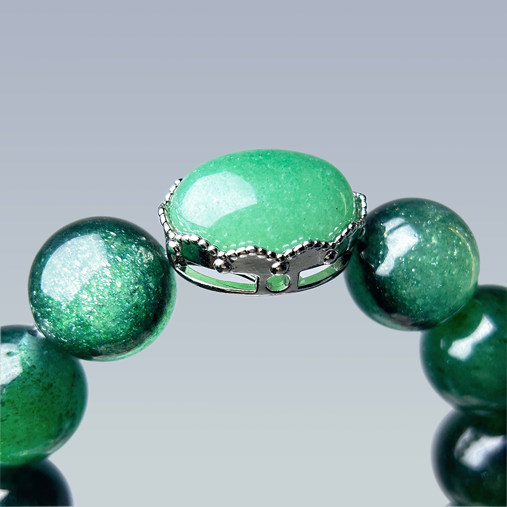 Macro view of the oval aventurine centerpiece set in a decorative silver crown bezel, highlighting the crystal's smooth surface and vivid green tone.