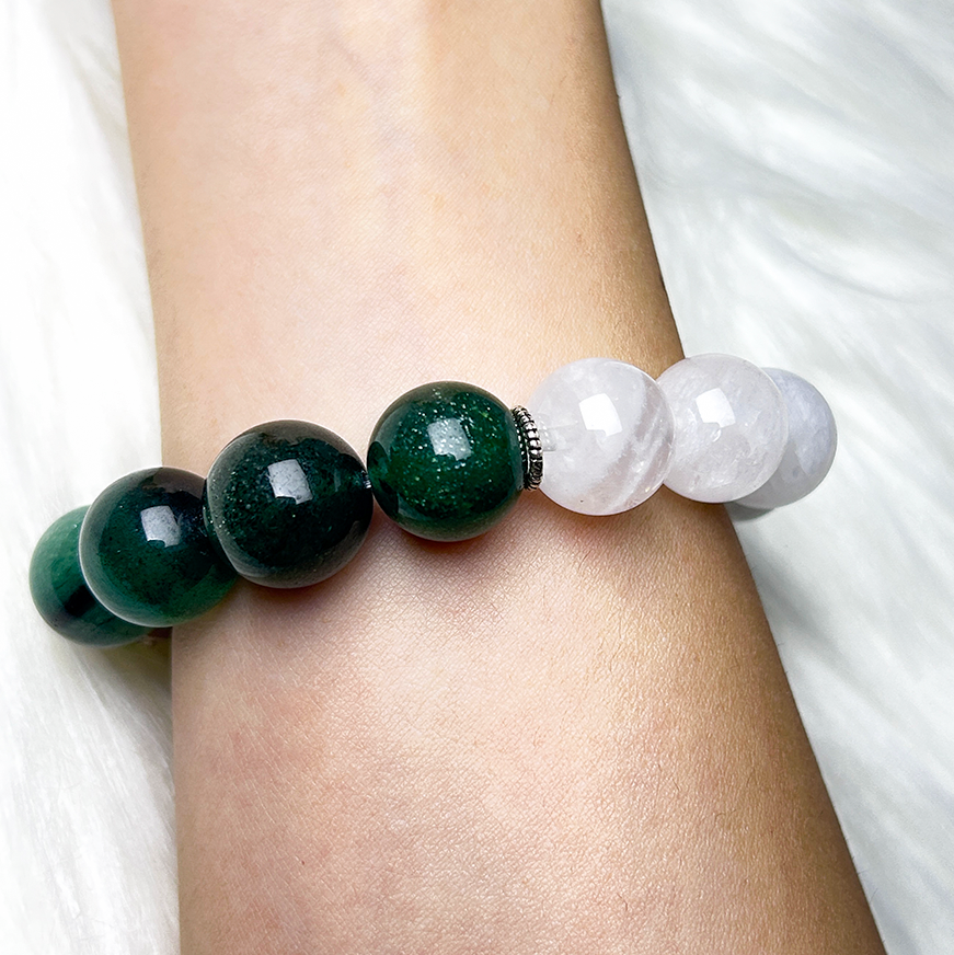 Wrist shot of the crystal bracelet with alternating green strawberry quartz and white phantom quartz beads, highlighting its natural sheen and elegant gradient.