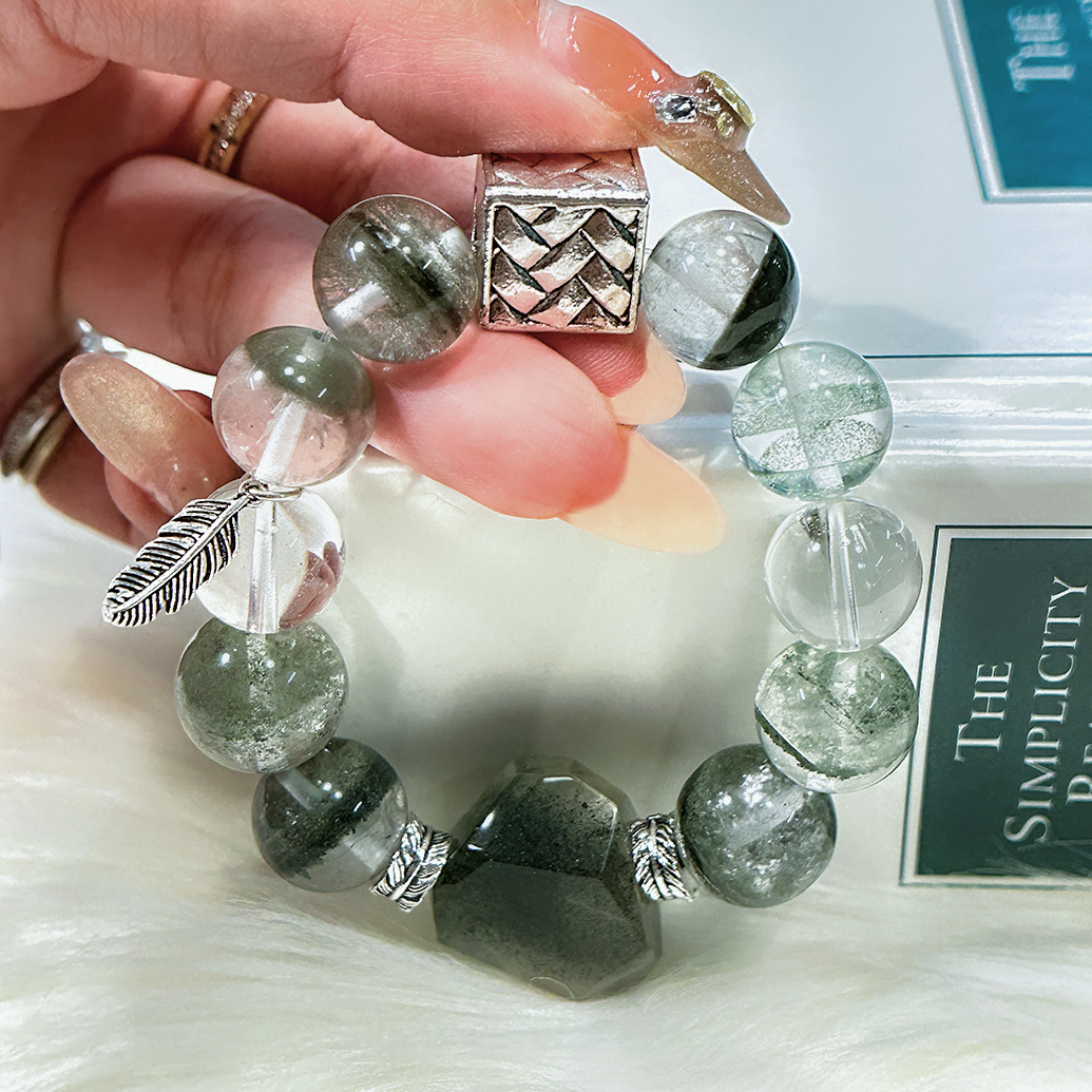 Hand holding Green Phantom Quartz and Clear Quartz bracelet with silver spacers.