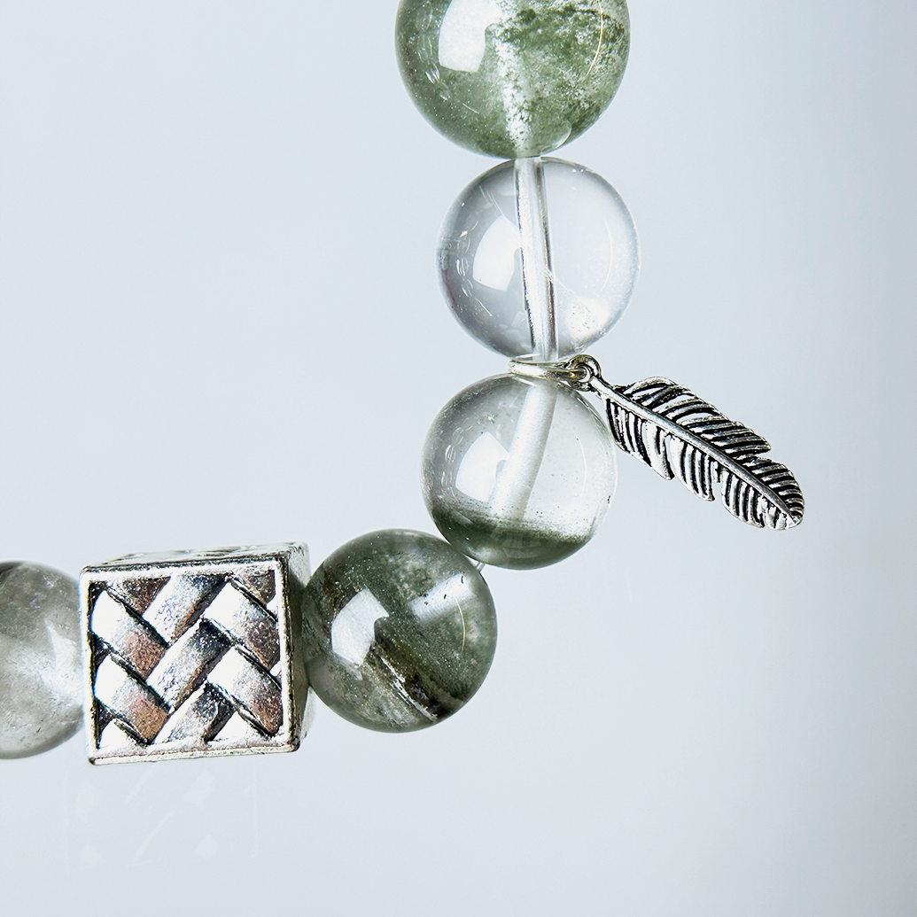 Close-up of Green Phantom and Clear Quartz beads with detailed feather charm