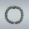 Handmade smoky quartz bracelet with glossy round beads, featuring a faceted black rutilated quartz centerpiece and silver flower charm accent.