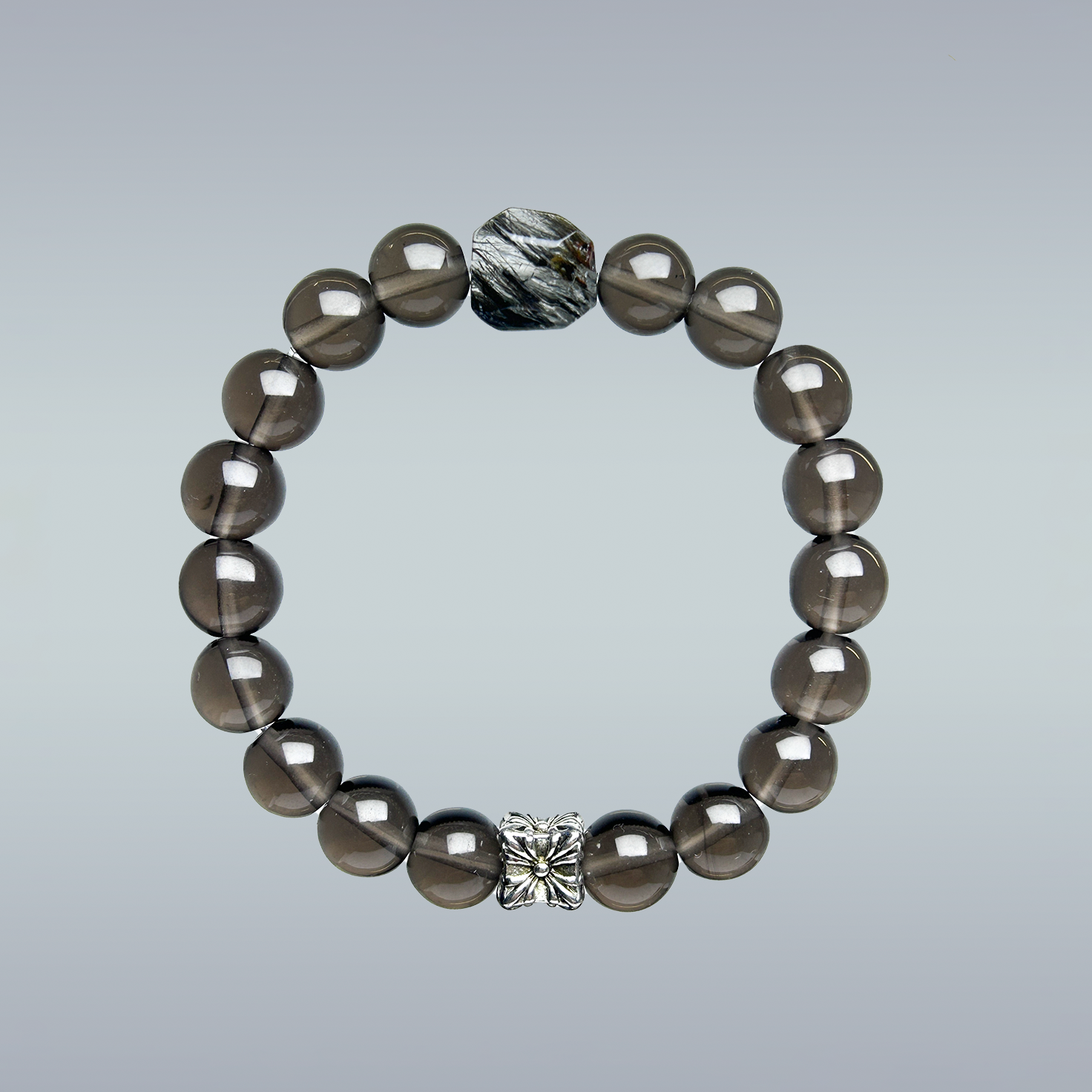 Handmade smoky quartz bracelet with glossy round beads, featuring a faceted black rutilated quartz centerpiece and silver flower charm accent.