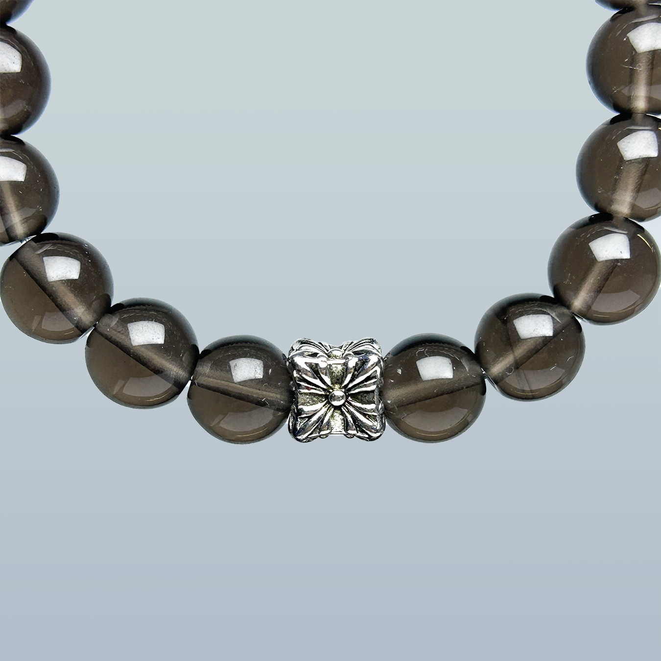 Close-up of smoky quartz crystal bracelet highlighting the detailed silver flower charm and polished natural quartz beads for healing energy.