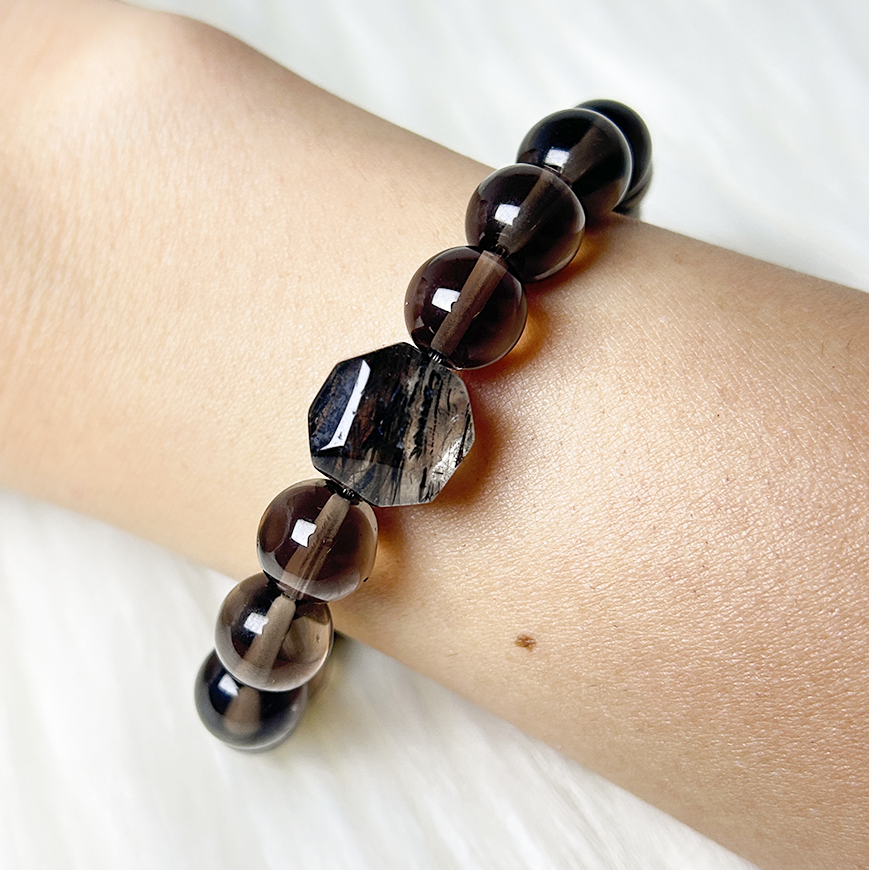 Smoky quartz and rutilated quartz bracelet worn on wrist, featuring protective gemstone beads.