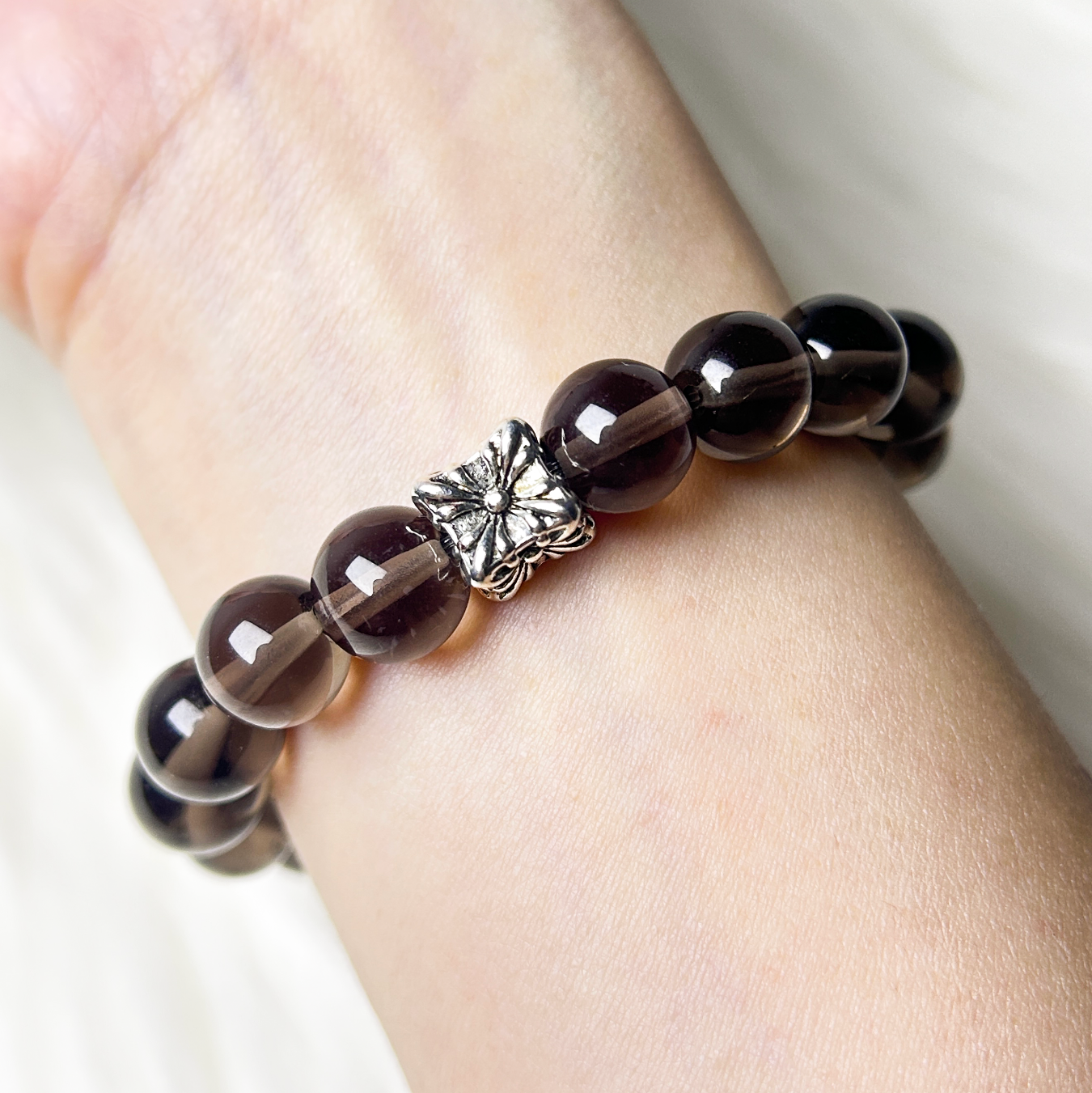 smoky quartz bracelet on wrist back view, focusing the shining silver charm.