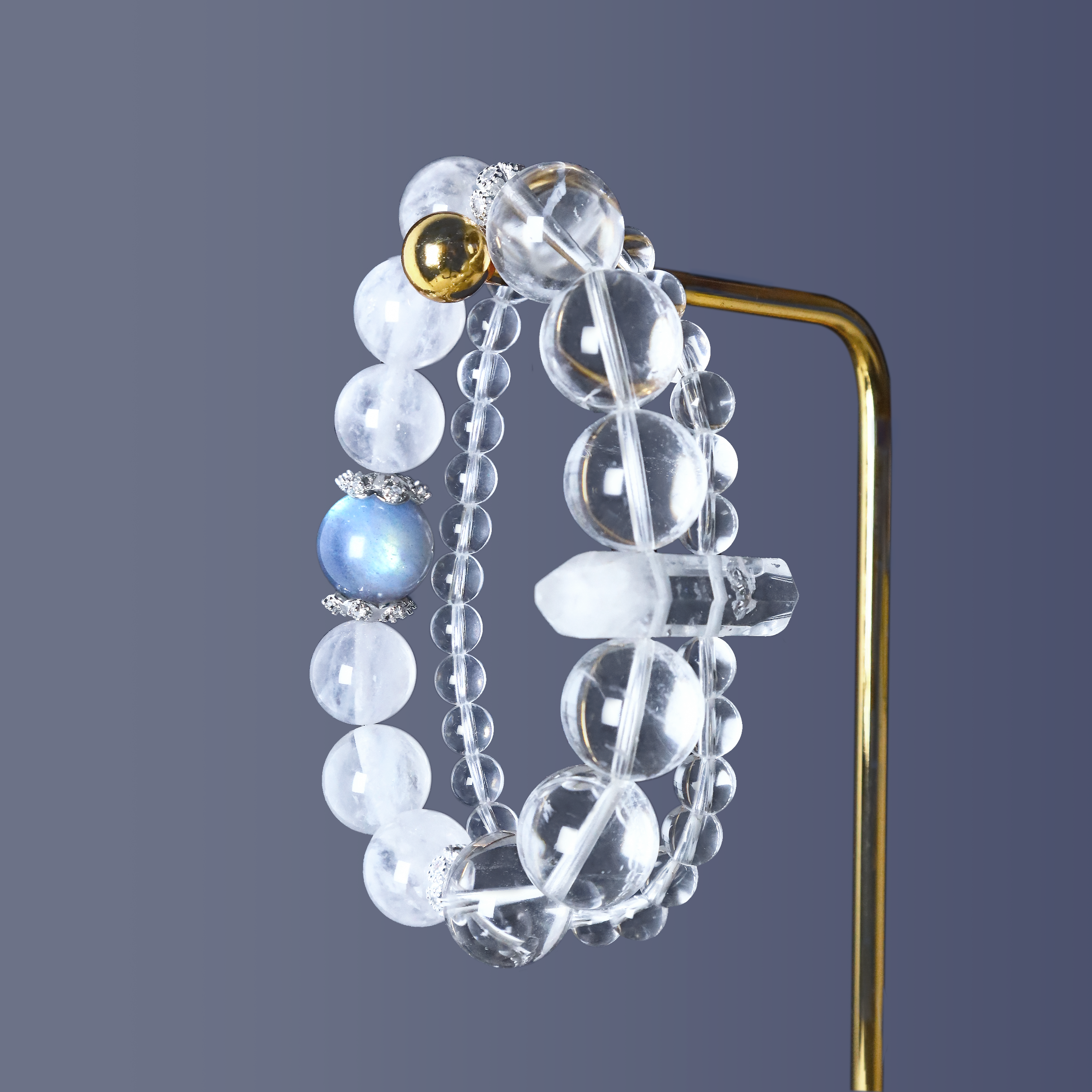 Double-layer bracelet made with Clear Quartz, Clear Phantom Quartz linkage piece, White Rabbit Hair Rutilated Quartz, and labradorite, displayed on gold stand