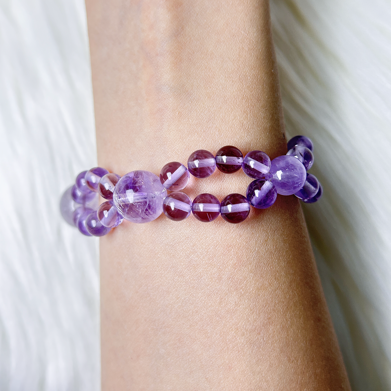 Double layered amethyst bracelet displayed on wrist with alternating violet bead sizes
