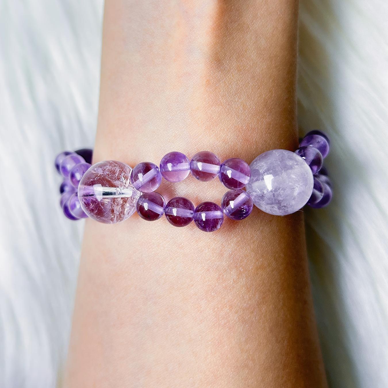 Back view close-up of double layered amethyst bracelet worn on wrist showing glossy purple beads