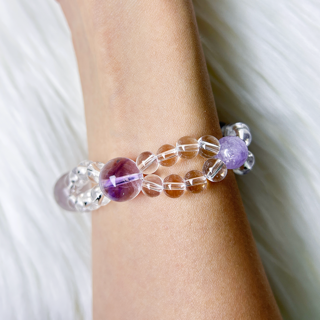 Double layered purple crystal bracelet made with amethyst and clear quartz worn on wrist side view