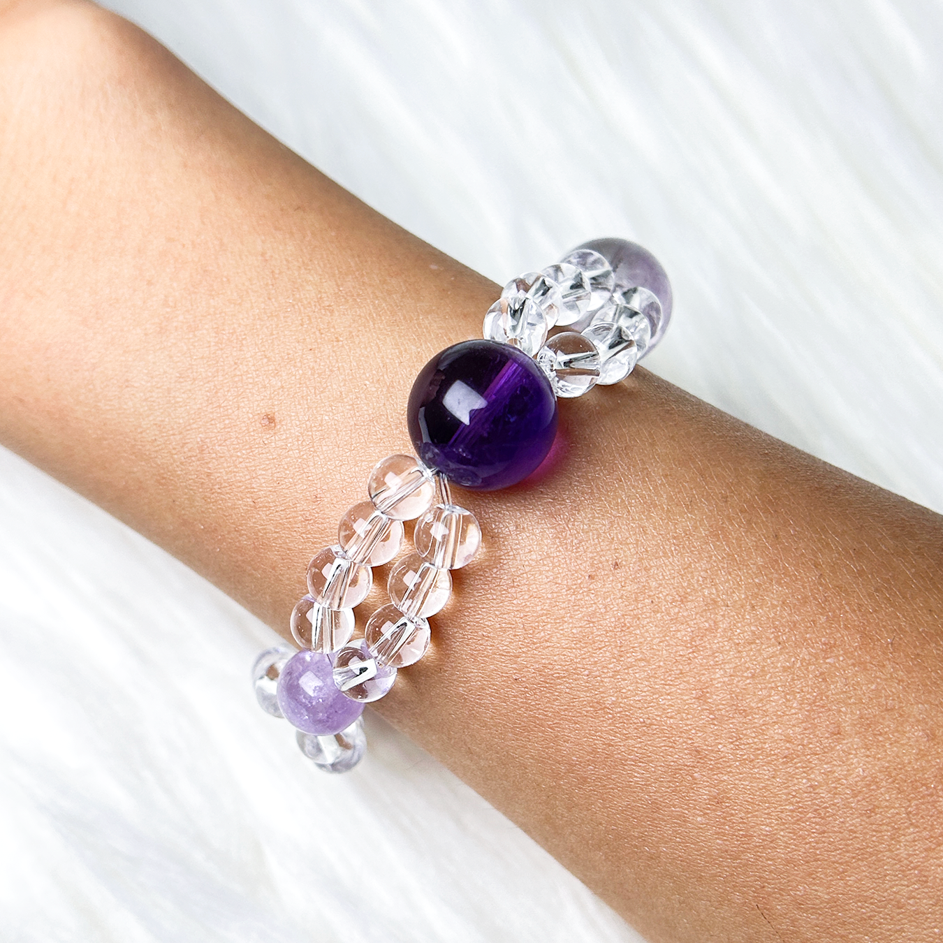 Top view of double layered purple and clear quartz bracelet worn on wrist 