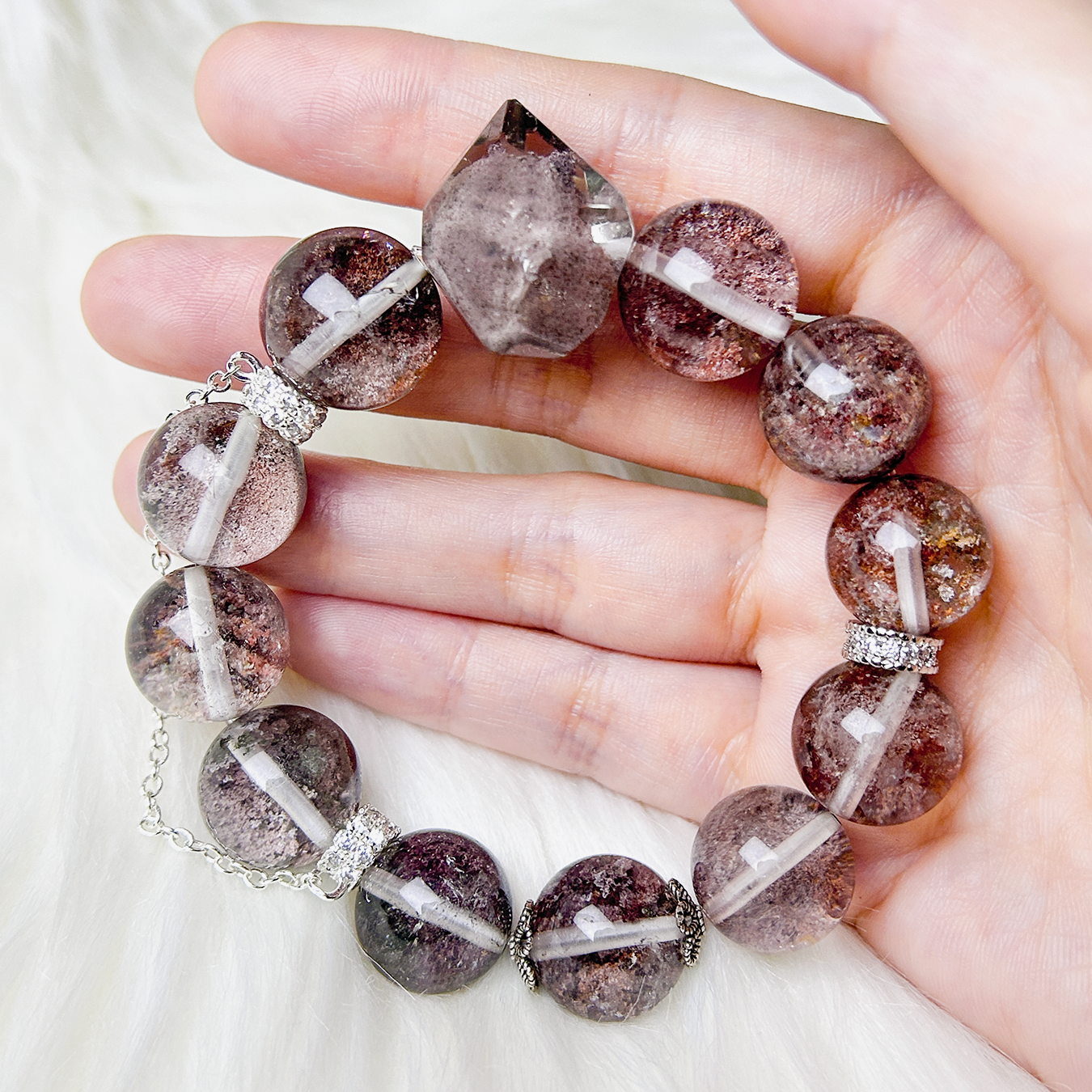 Phantom Quartz bracelet displayed in hand, showcasing the pointed centerpiece and rich mineral inclusions within each bead.