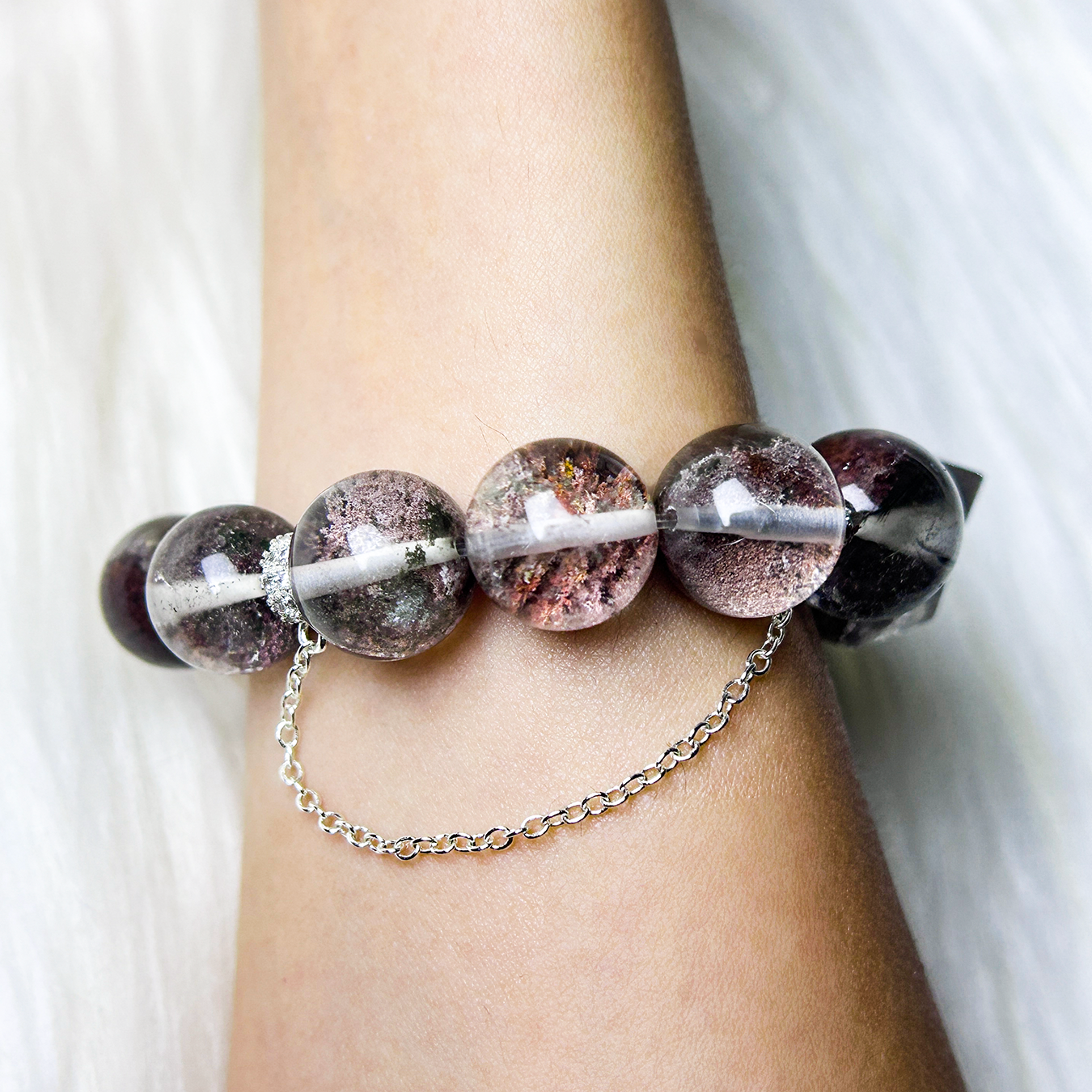 Back view of Phantom Quartz bracelet on wrist, showing the protective silver chain and the uniform natural bead texture