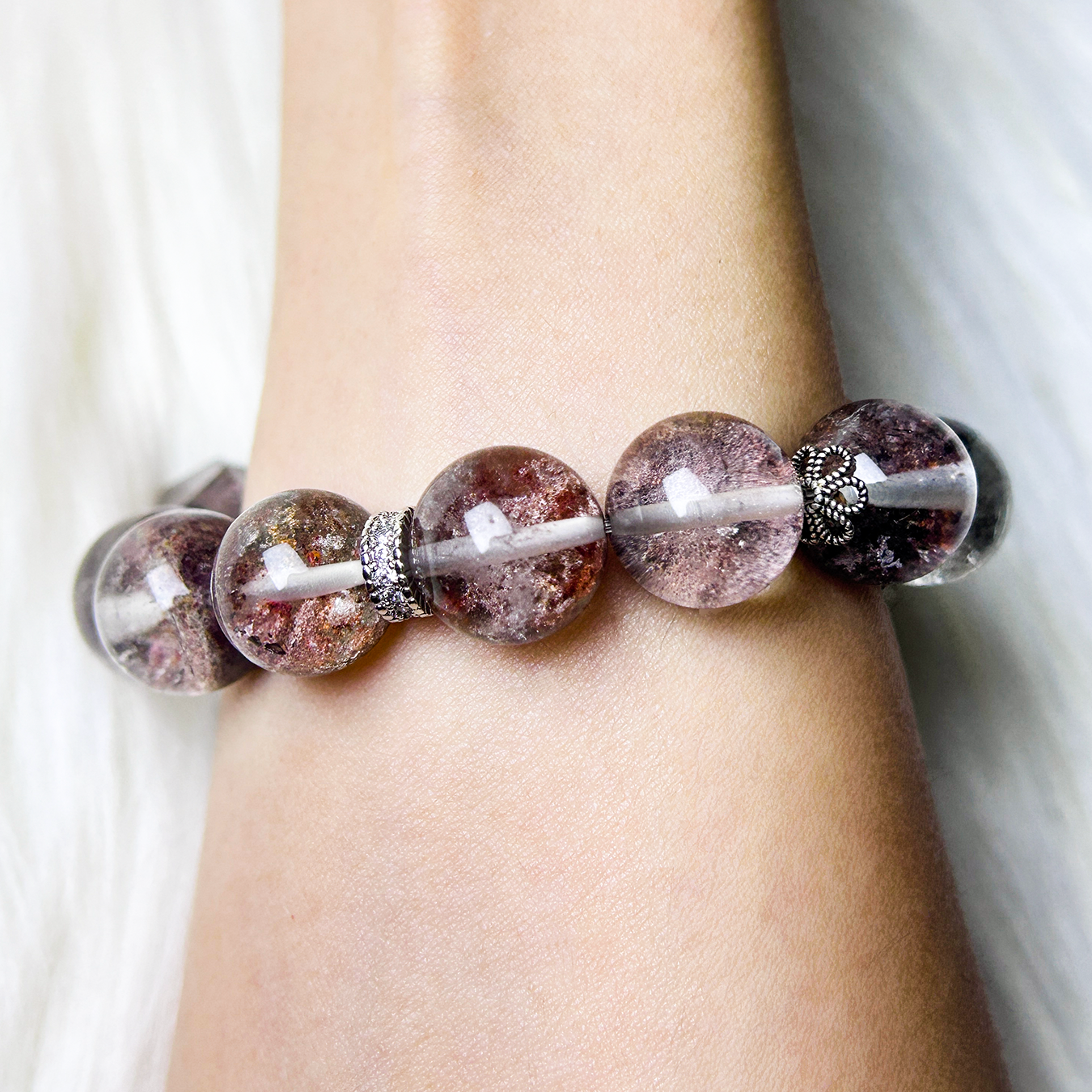 Close-up wrist shot of Phantom Quartz bracelet with sparkling silver spacers and translucent earthy-toned crystal beads.