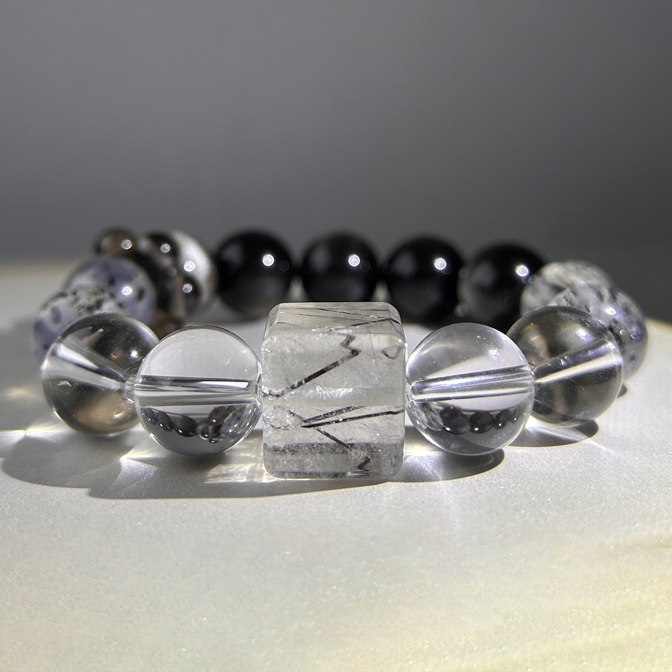 Studio-lit Monochrome Vein bracelet showing gradient shine from clear quartz to black obsidian under soft light.