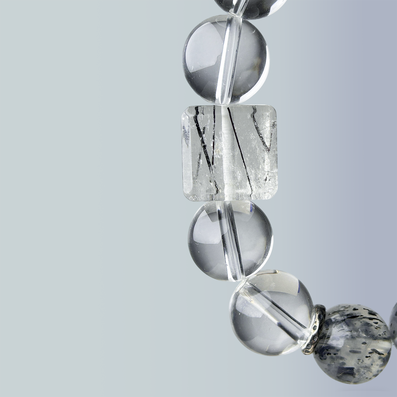 Macro shot of rutilated quartz cube centerpiece framed by clear quartz beads in the Monochrome Vein bracelet.