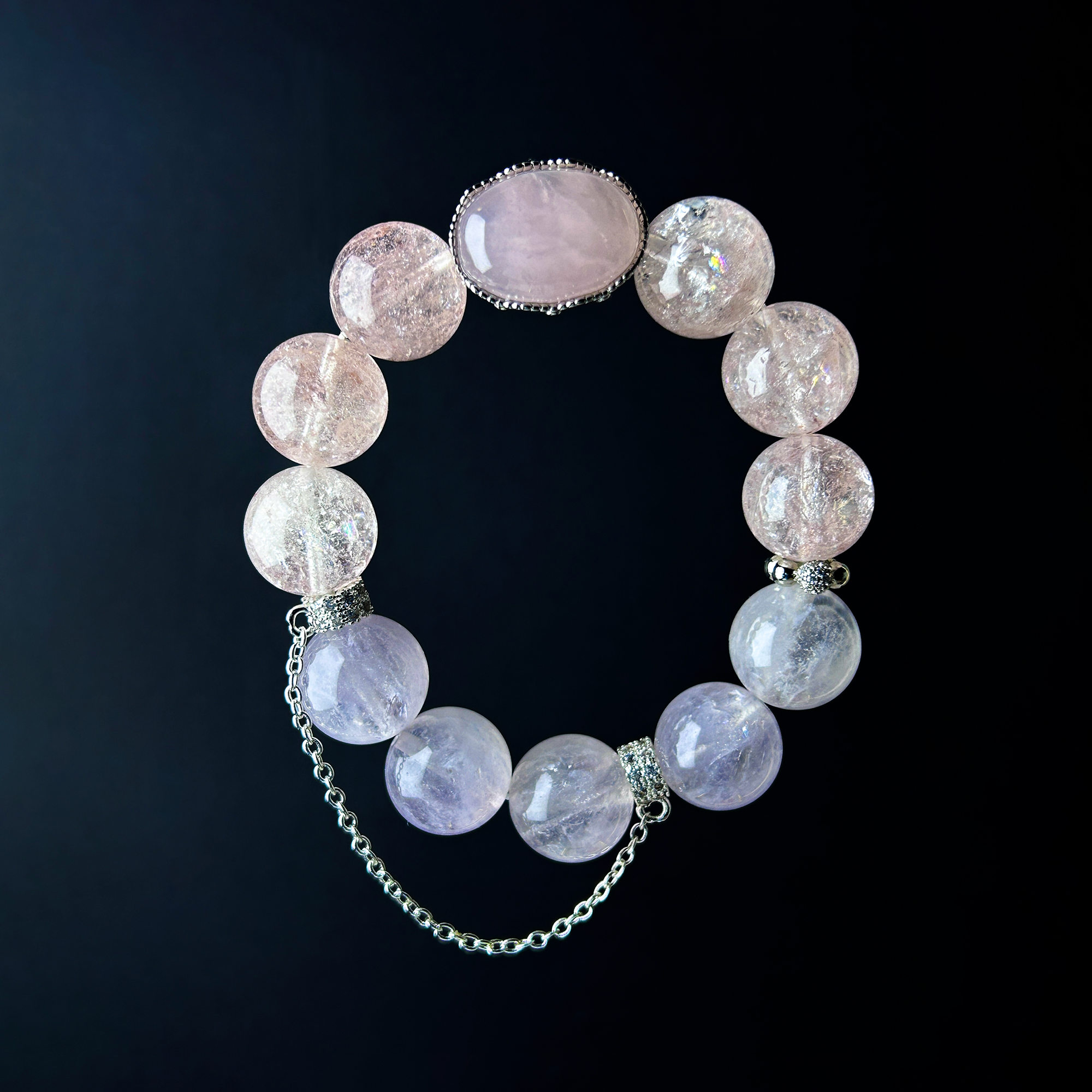 Pink tone crystal bracelet with rose quartz centerpiece hanging view in black background.