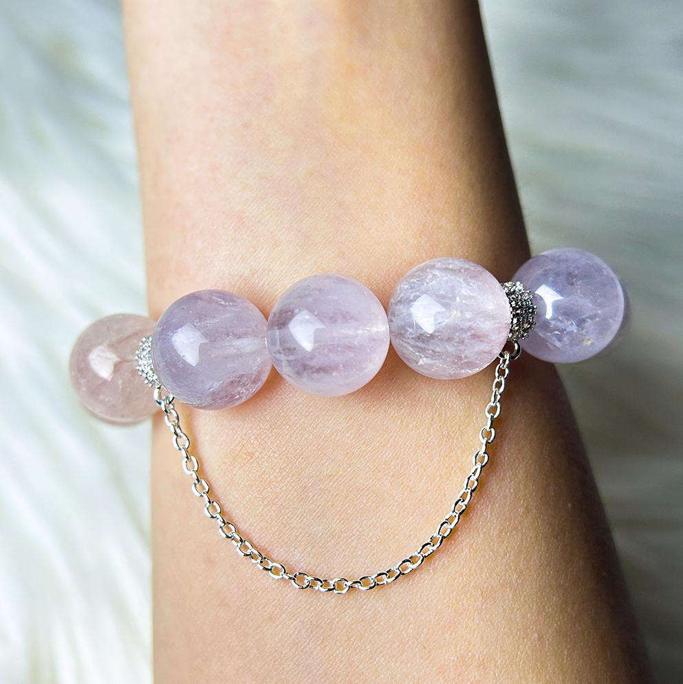 Back view of the crystal bracelet showing light purple rutilated quartz beads and a silver safety chain clasp detail.