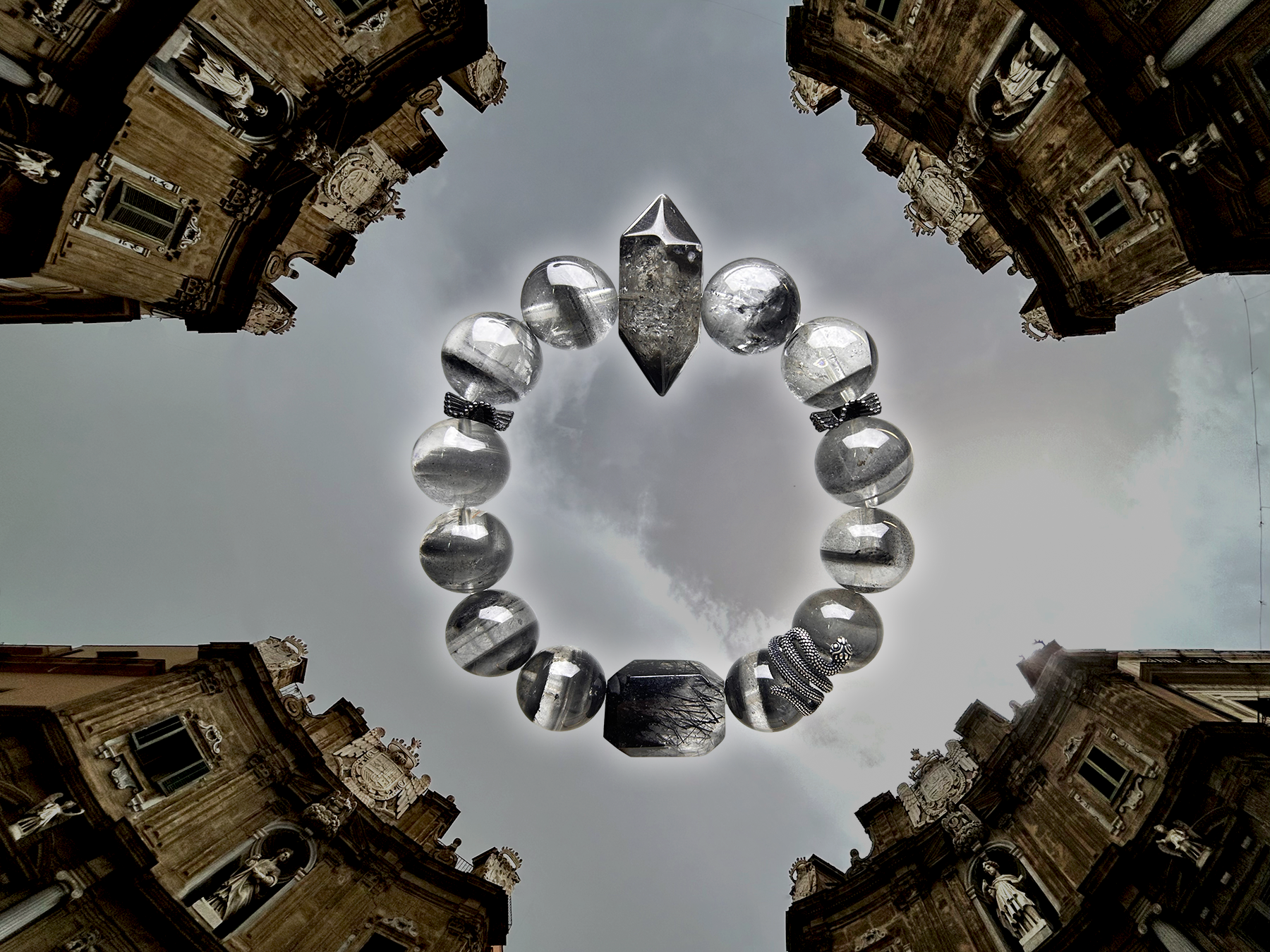 Rutilated quartz and phantom quartz bracelet in metallic grey tones set against architectural sky background