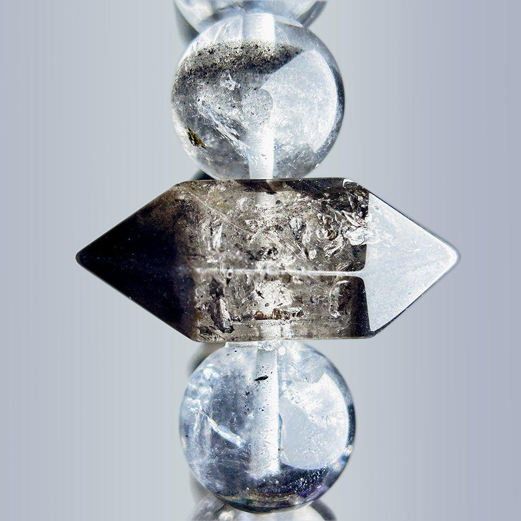 Macro image of the double-terminated Rutilated Quartz centerpiece bead, showing natural inclusions and geometric form between two clear-black quartz spheres.