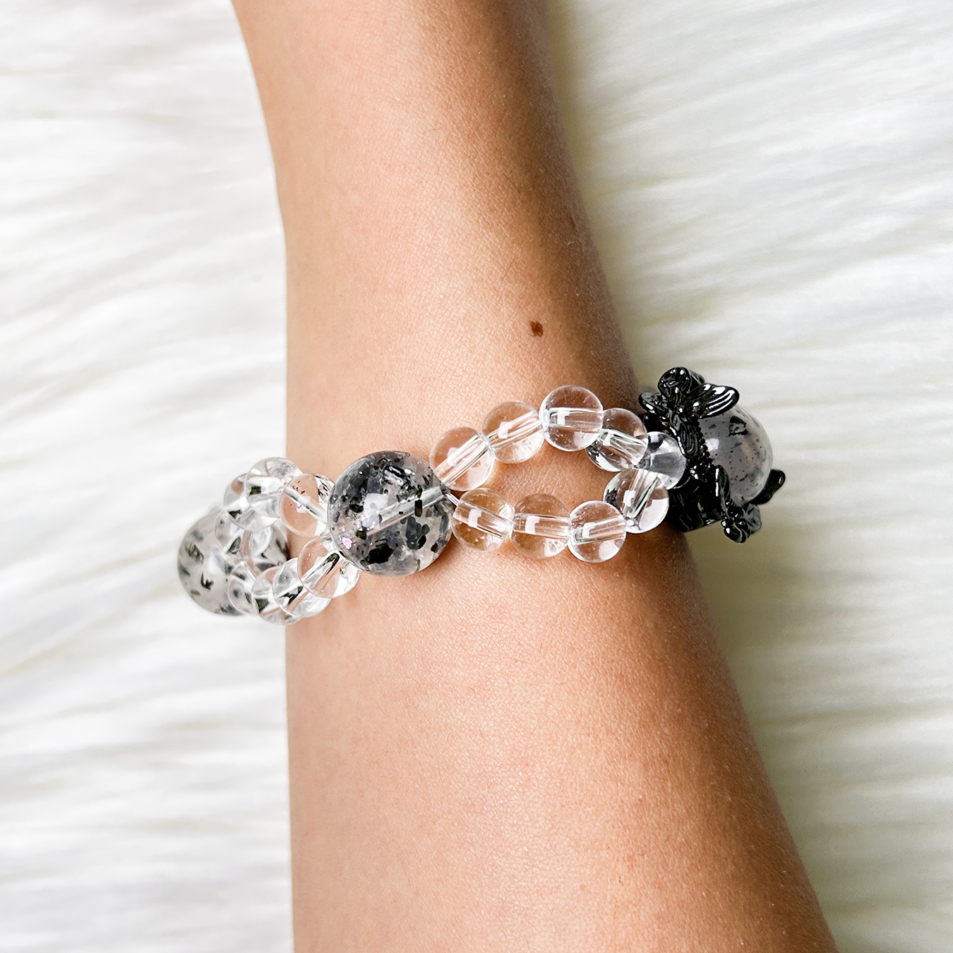 Side view of Noir Mist bracelet highlighting floral charm and transparent clear-quartz layers.