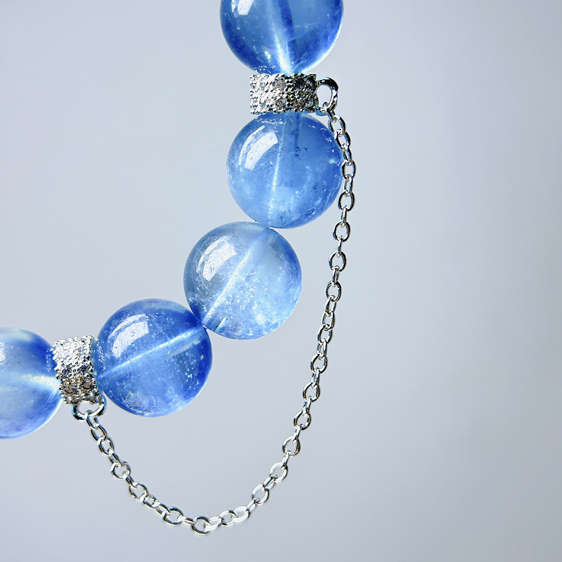 Close-up of aquamarine bracelet with silver chain and crystal spacer