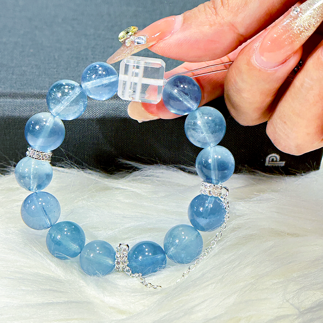 Hand holding aquamarine bracelet with white phantom quartz cube centerpiece