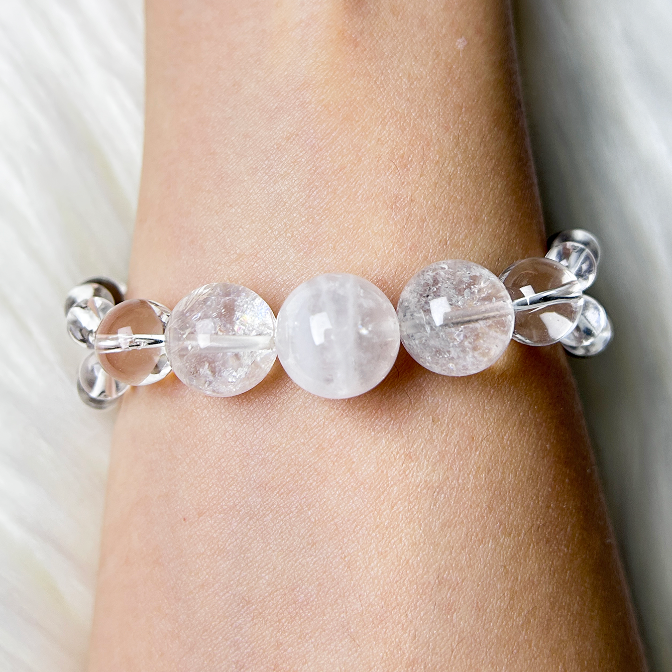 Clear quartz crystal bracelet with round natural white crystal beads displayed on wrist.