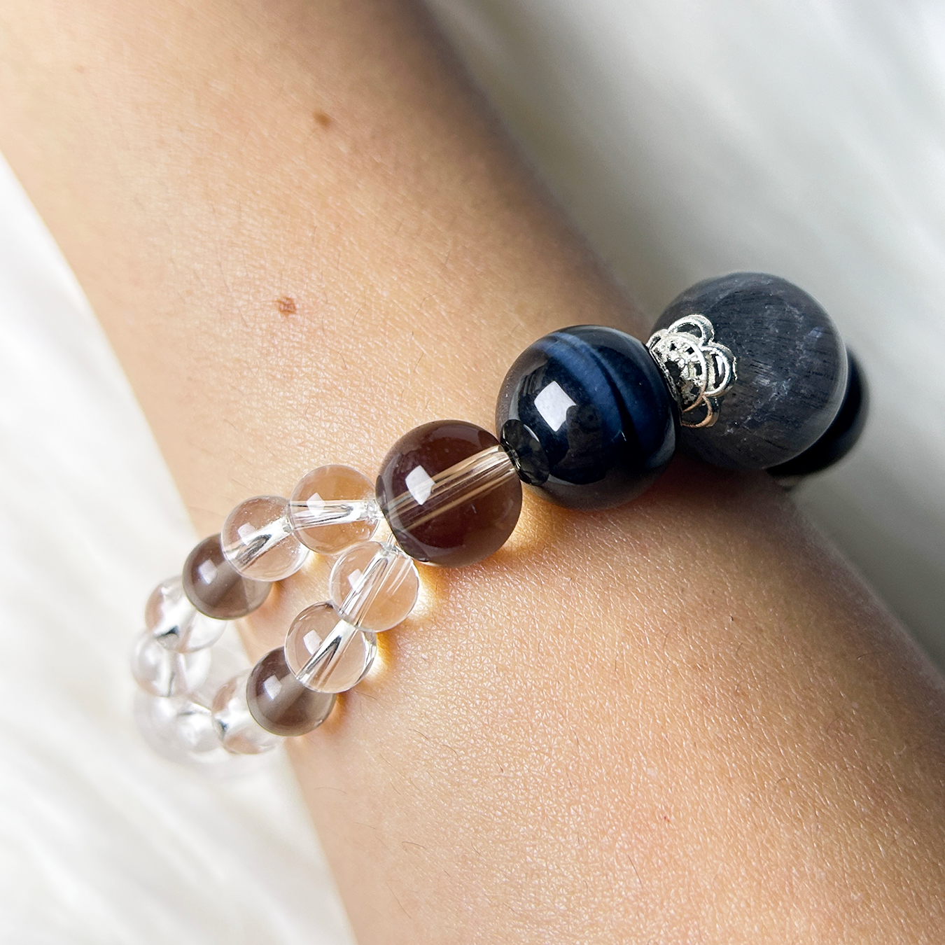 Close-up of a double-strand crystal bracelet featuring Blue Tiger’s Eye, Smoky Quartz, and Clear Quartz beads on a model’s wrist, radiating spiritual focus and calm energy.