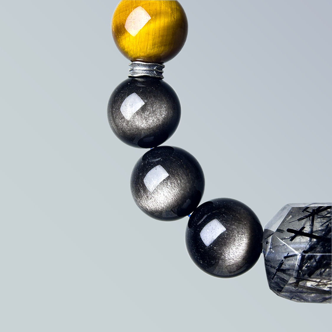Detail view of the bracelet’s transition from yellow tiger’s eye to metallic cat’s eye beads, emphasizing the natural sheen and precise silver ring spacer.