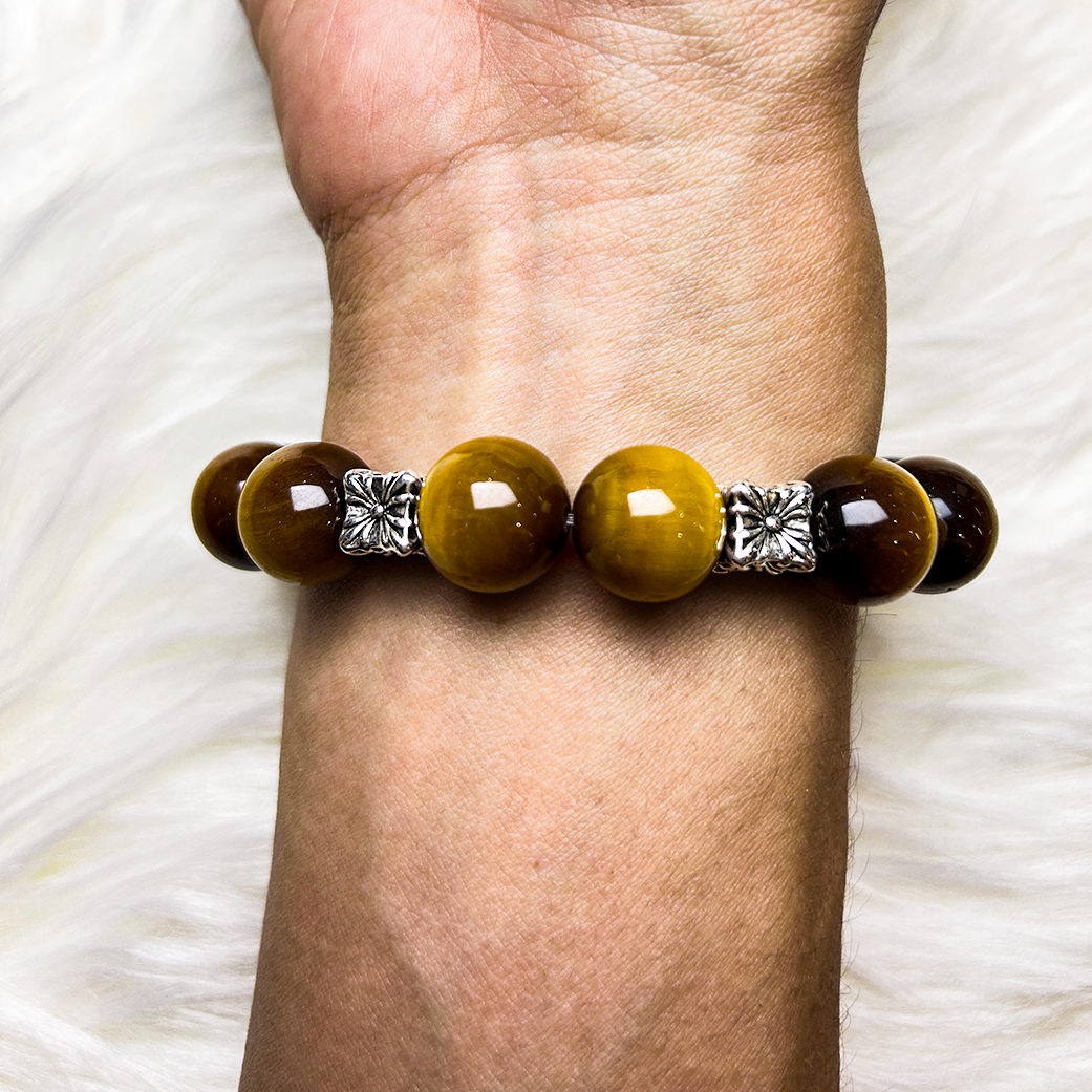 Rear view of a crystal bracelet with vibrant golden yellow tiger’s eye beads, accented with silver floral spacers, worn on the wrist and captured under soft natural lighting.