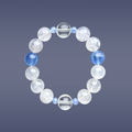 Hang lay of Aquamarine, Clear Quartz, and White Rabbit Hair Rutilated Quartz crystal bracelet on blue background.
