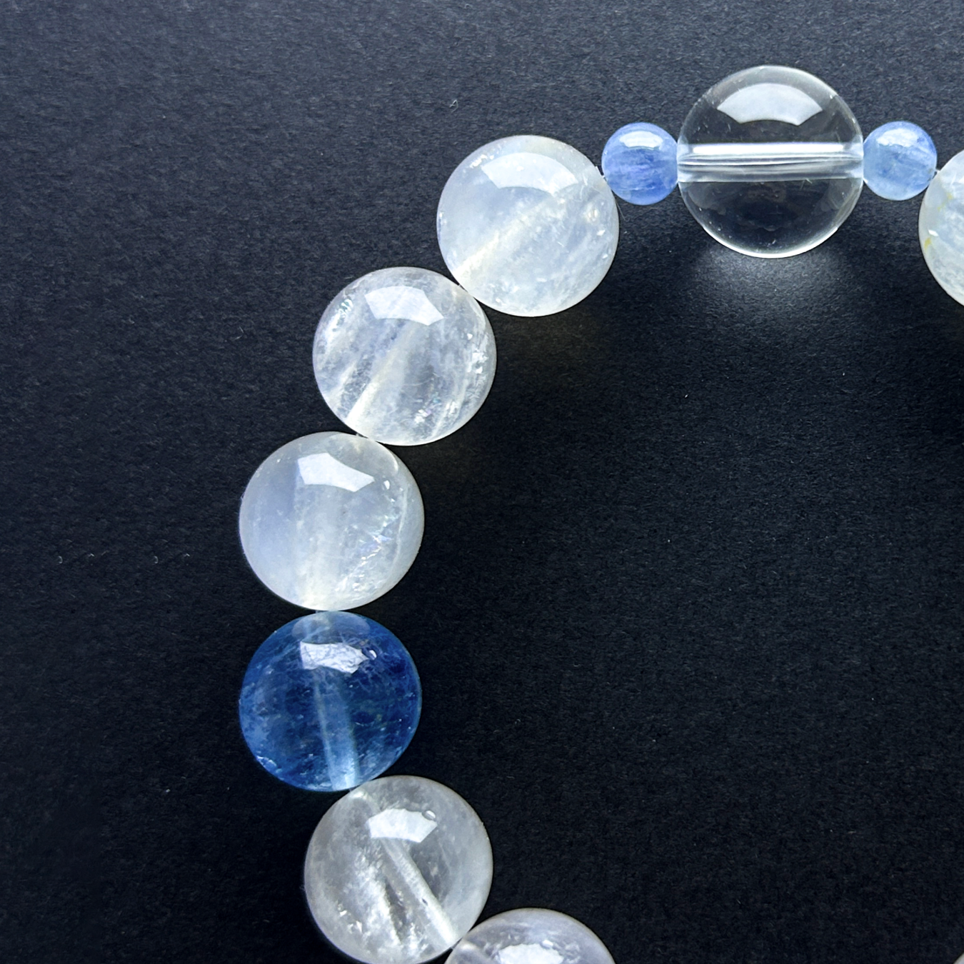 Flat lay of Aquamarine, Clear Quartz, and White Rabbit Hair Rutilated Quartz crystal bracelet on black background