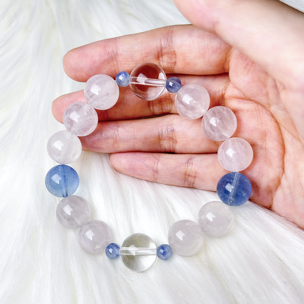 Hand holding soft-toned gemstone bracelet with Clear Quartz center and Aquamarine accents