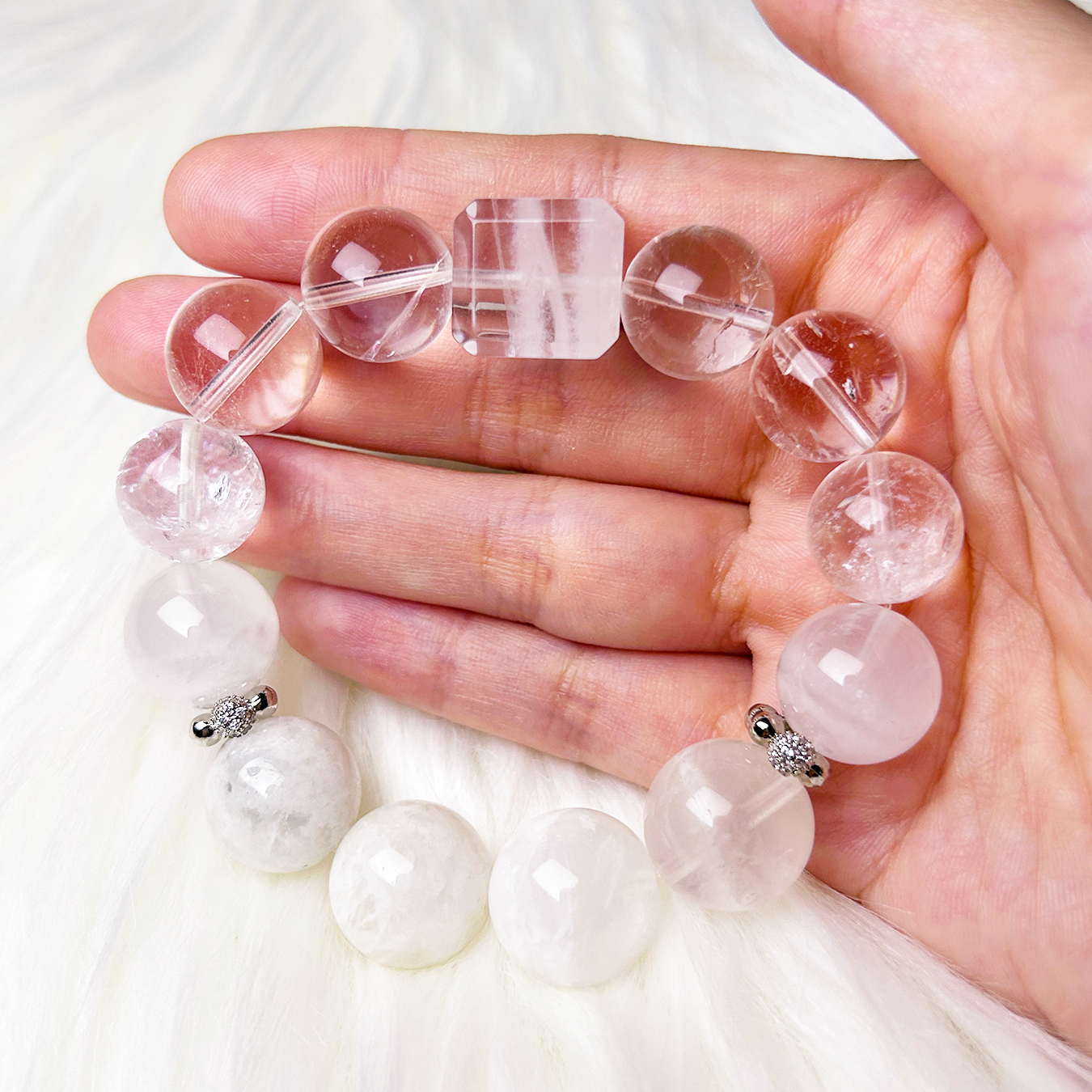 Hand-holding shot of the white phantom and clear quartz bracelet, revealing the bracelet’s size and natural translucency under soft lighting.