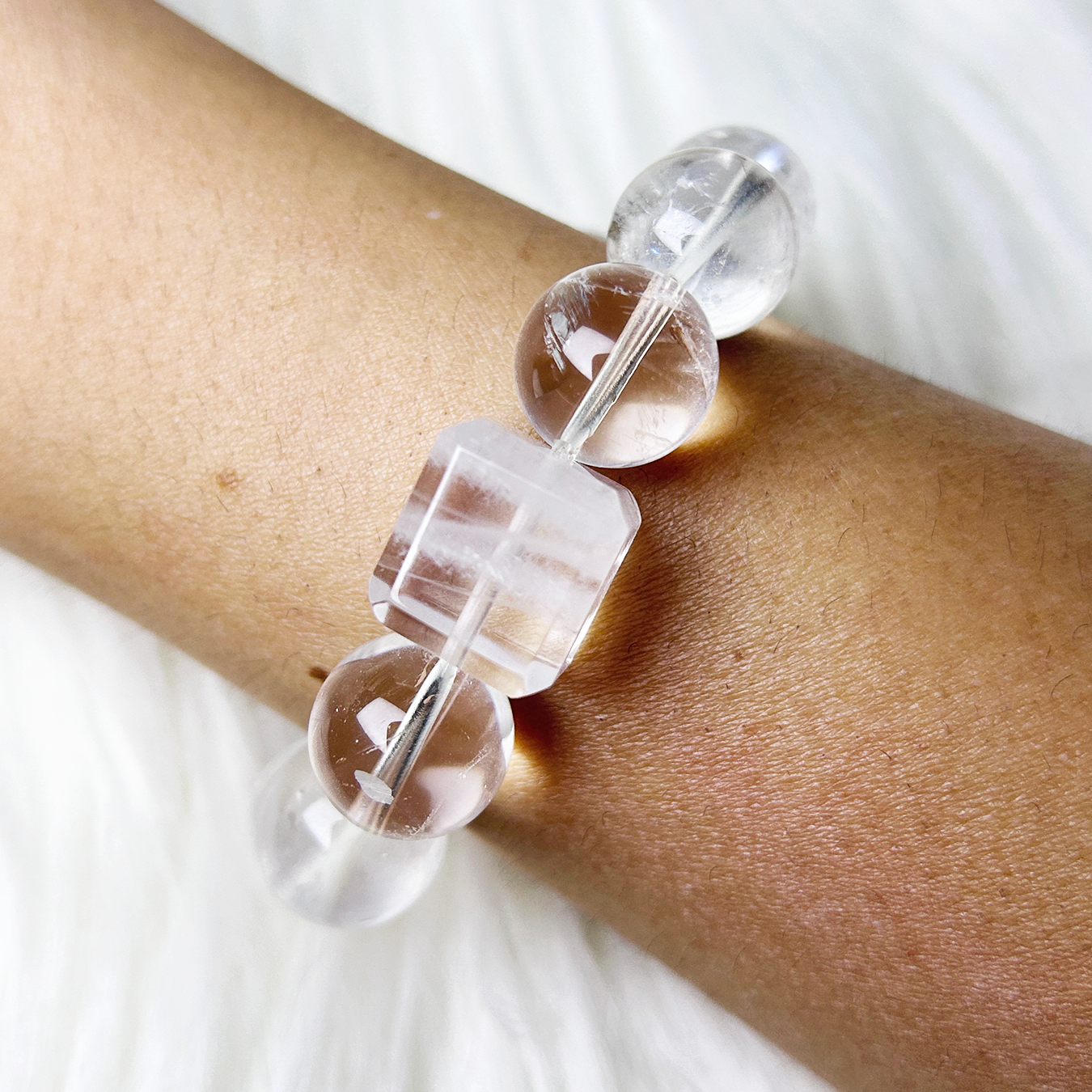 Wrist shot of the bracelet focusing on the rectangular clear quartz centerpiece, displaying its clean cut and luminous clarity against the skin.