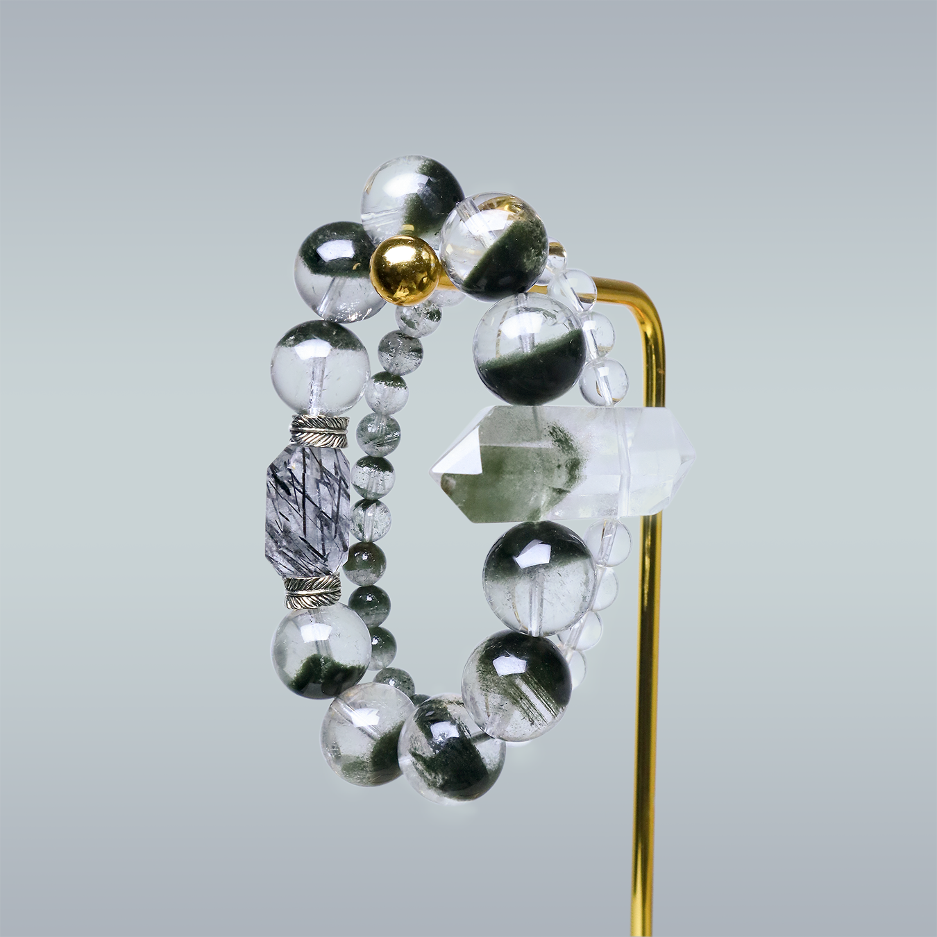 Double-layer bracelet with Green Phantom Quartz, Clear Quartz, and Clear Rutilated Quartz displayed on gold stand