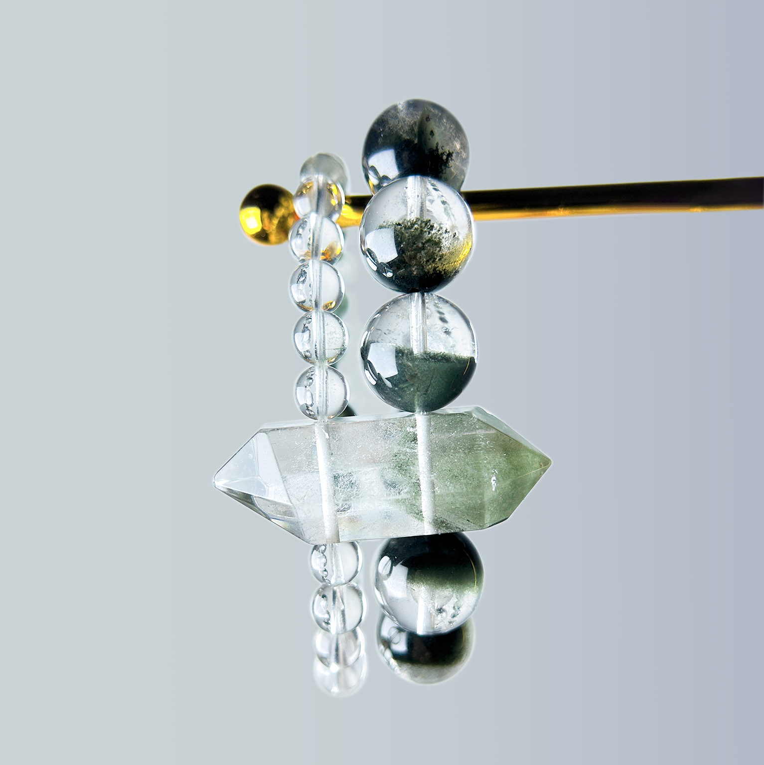 Close-up of Green Phantom Quartz double-terminated point and rounded beads on crystal bracelet