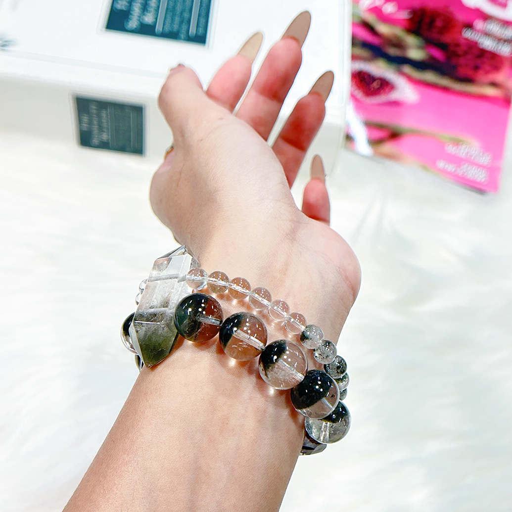 Wrist shot of double-layer bracelet with Green Phantom Quartz and Clear Quartz with books in background