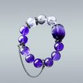 Hang-lay image of amethyst bracelet with light and dark beads, black snowflake accents, and a butterfly chain charm, displayed on a gradient gray background.