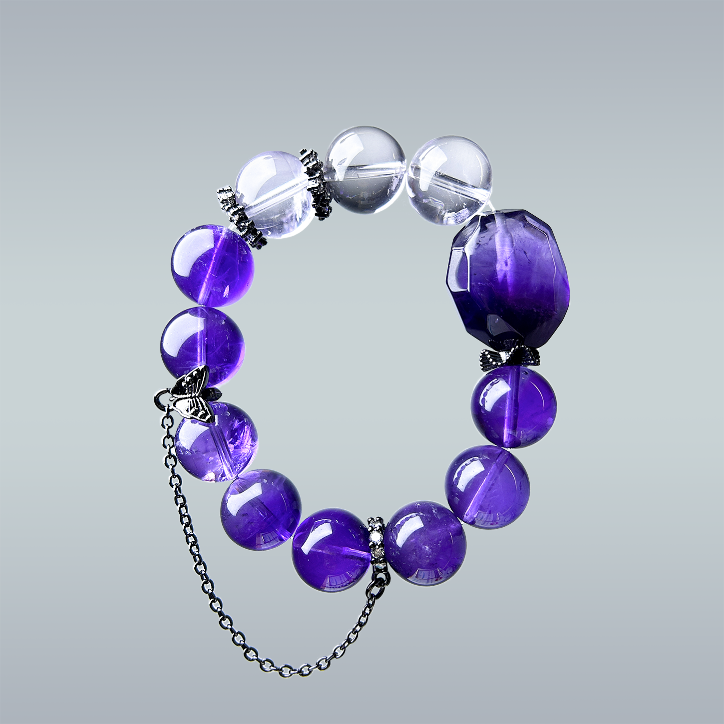 Hang-lay image of amethyst bracelet with light and dark beads, black snowflake accents, and a butterfly chain charm, displayed on a gradient gray background.