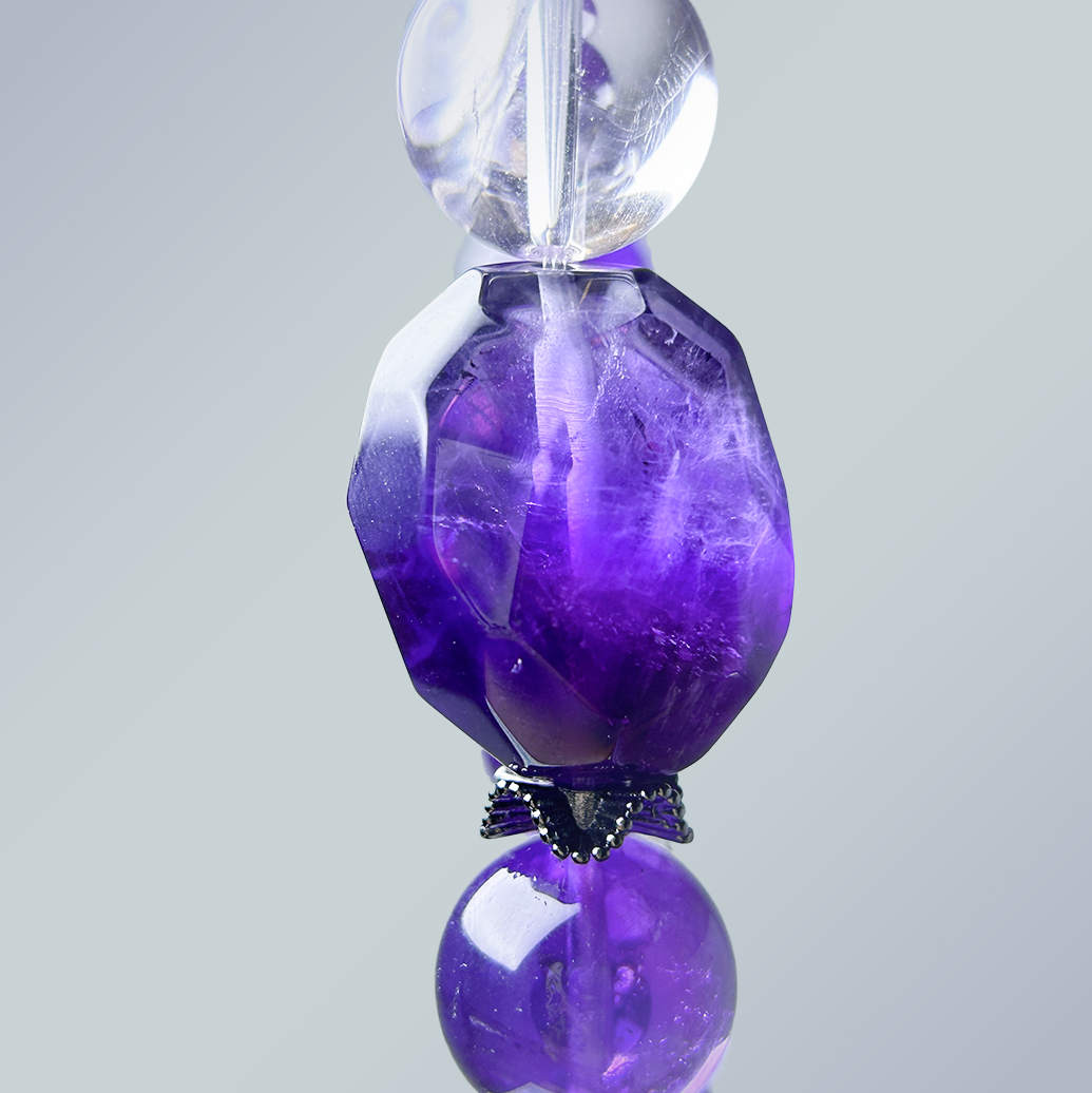 Macro shot of faceted dark amethyst centerpiece bead with surrounding clear quartz and silver-toned black spacer for detail emphasis.
