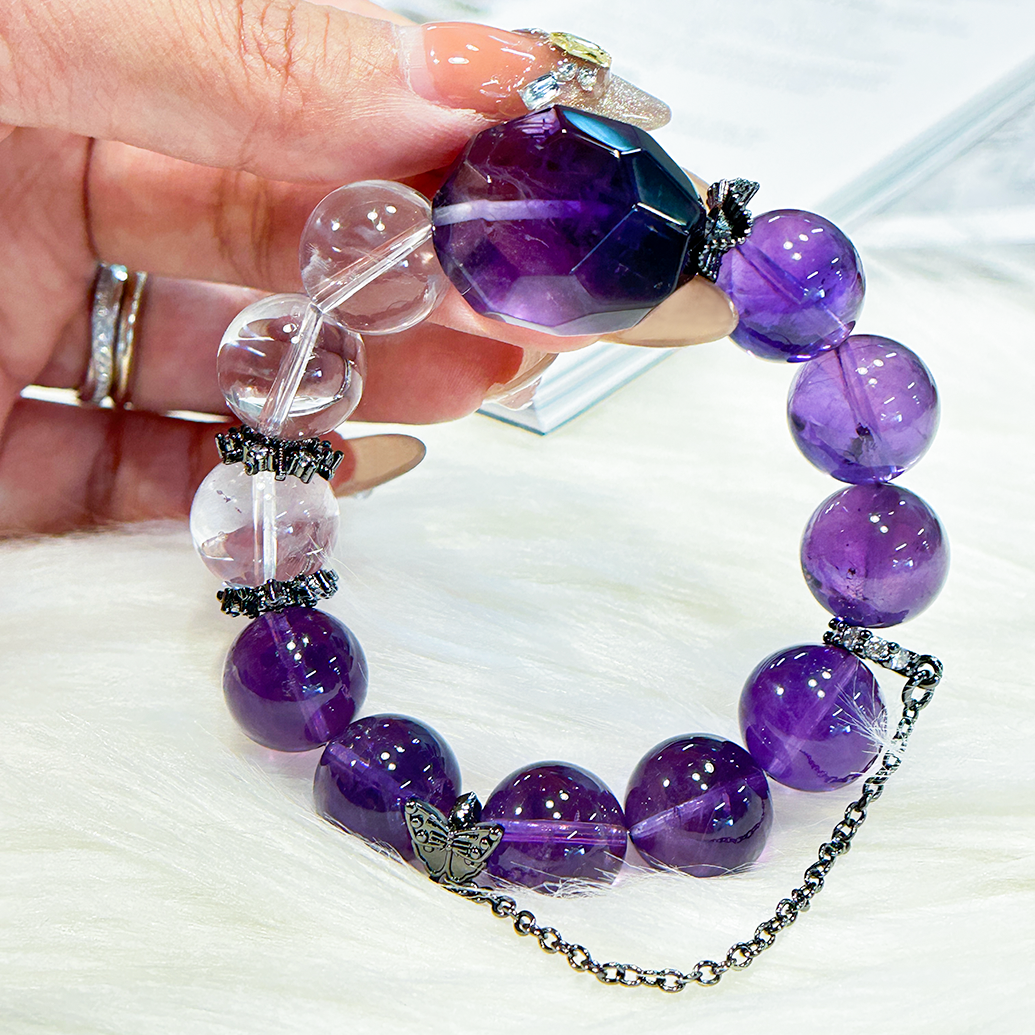 Close-up of hand holding the amethyst bracelet, highlighting the mix of clear and amethyst beads, black spacers, and the dark faceted centerpiece.